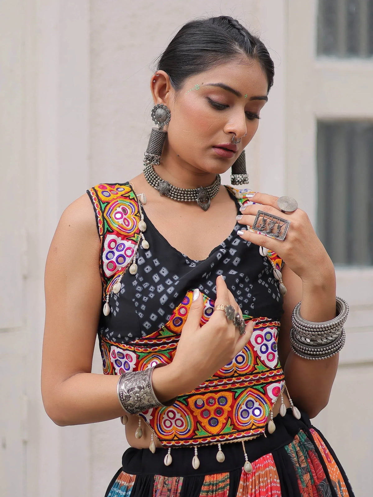 Woman in vibrant ethnic Indian blouse with mirror work, embroidery, and traditional silver jewelry.