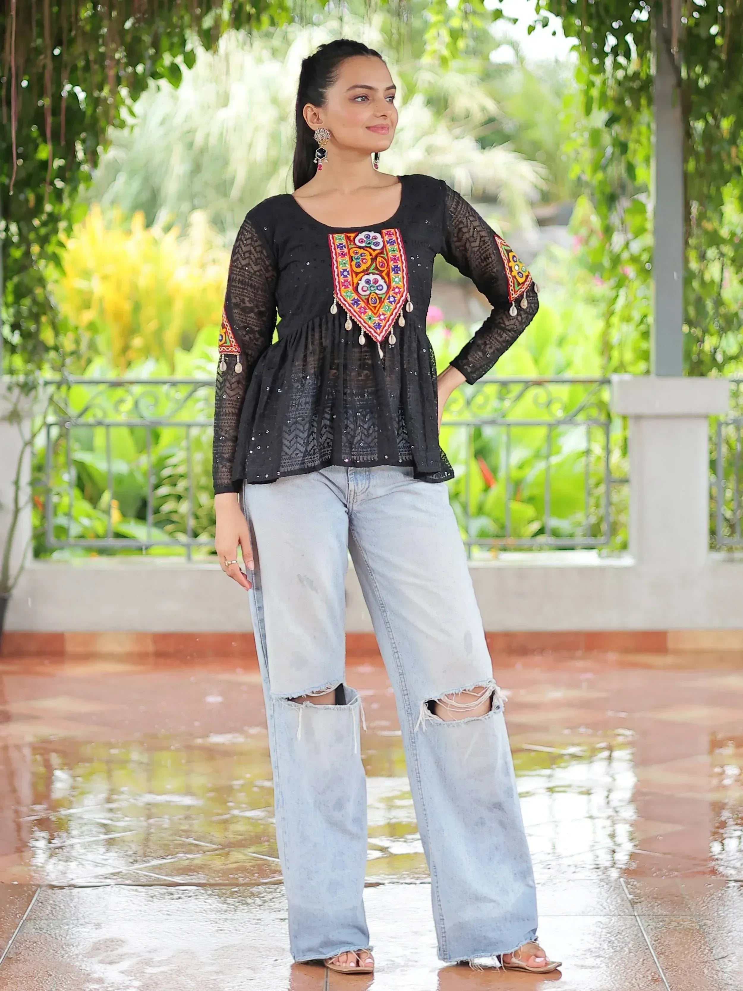 Black embroidered ethnic top with colorful mirror work paired with ripped denim jeans, perfect for casual fusion style.