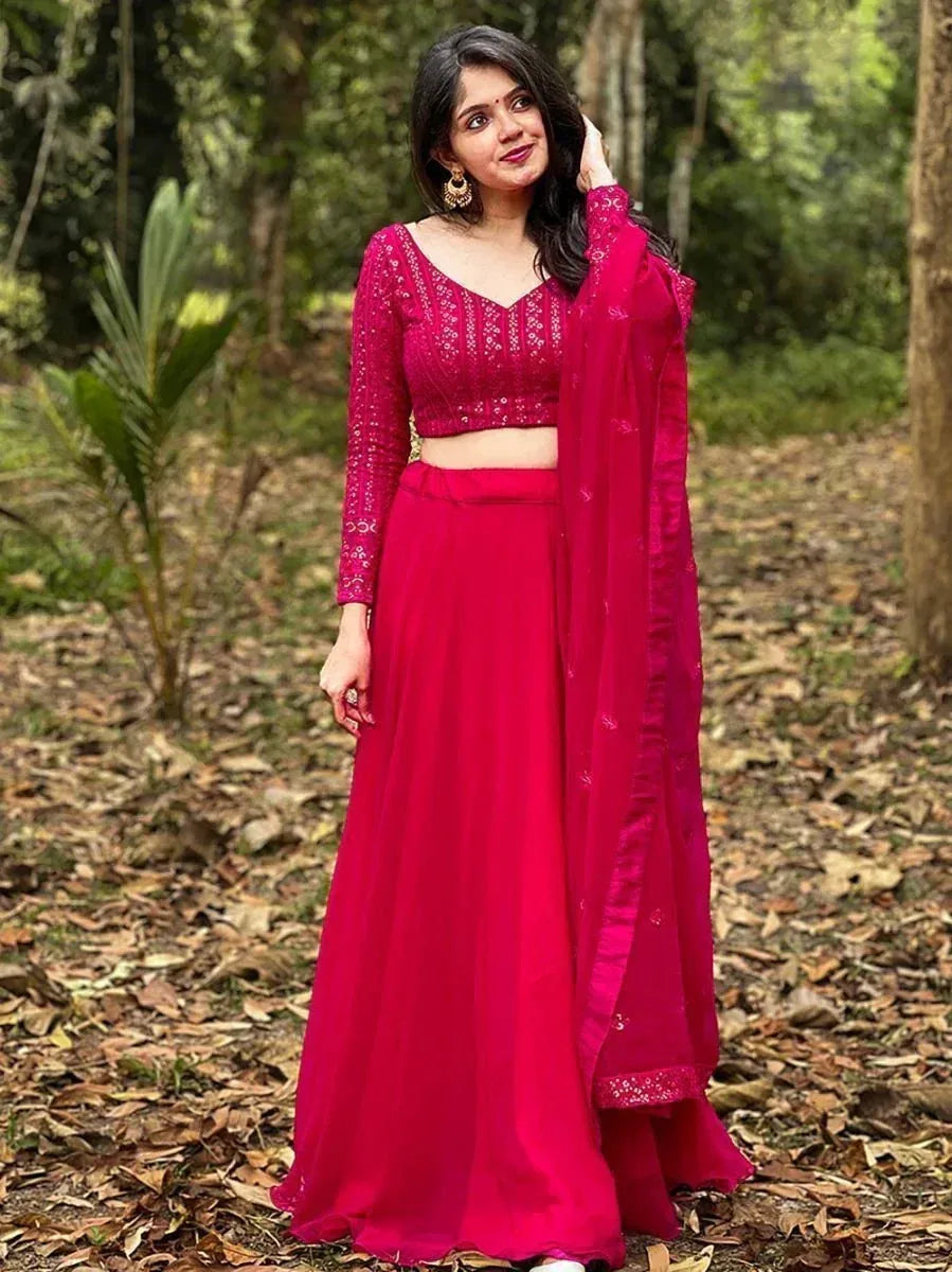 Woman in vibrant pink embroidered lehenga choli with sheer dupatta, styled for ethnic occasions