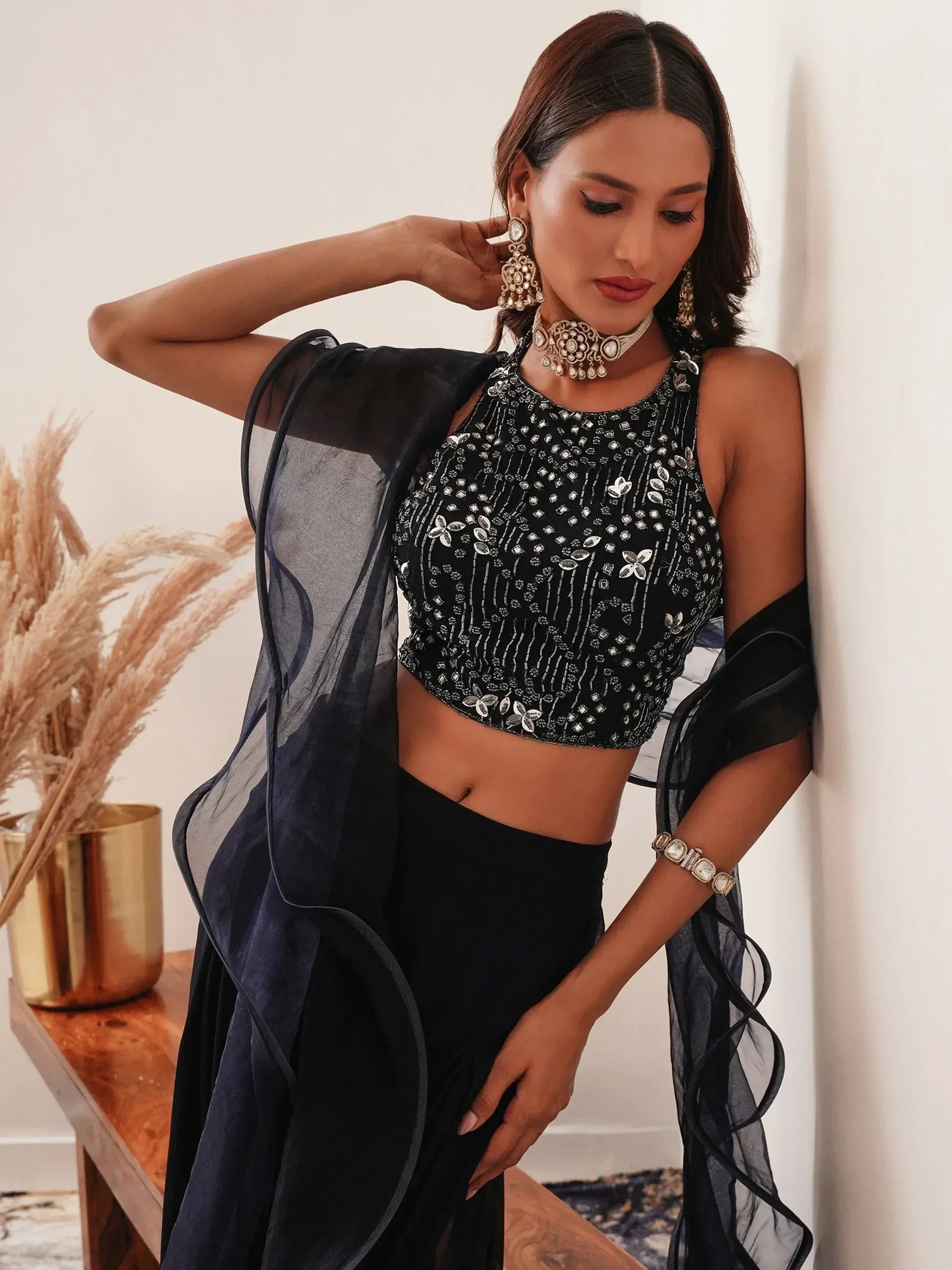 Woman in black sequined ethnic lehenga choli with dupatta, statement jewelry, indoors