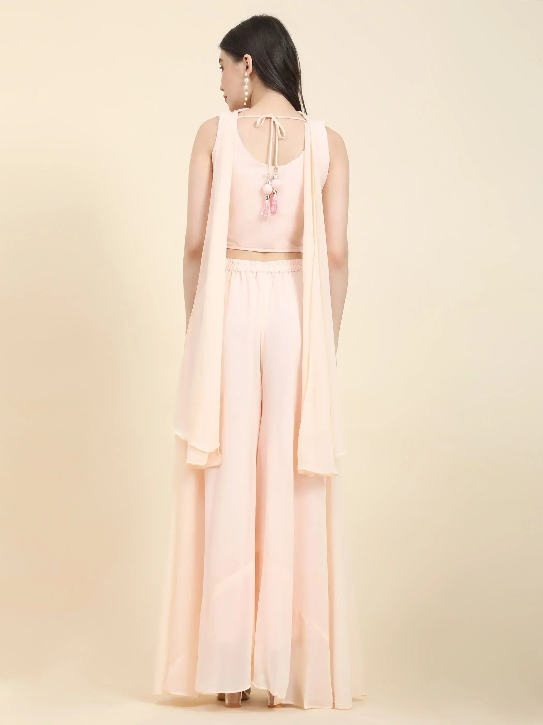 Woman in pastel pink ethnic crop top and palazzo pants with tassel tie-back, rear view