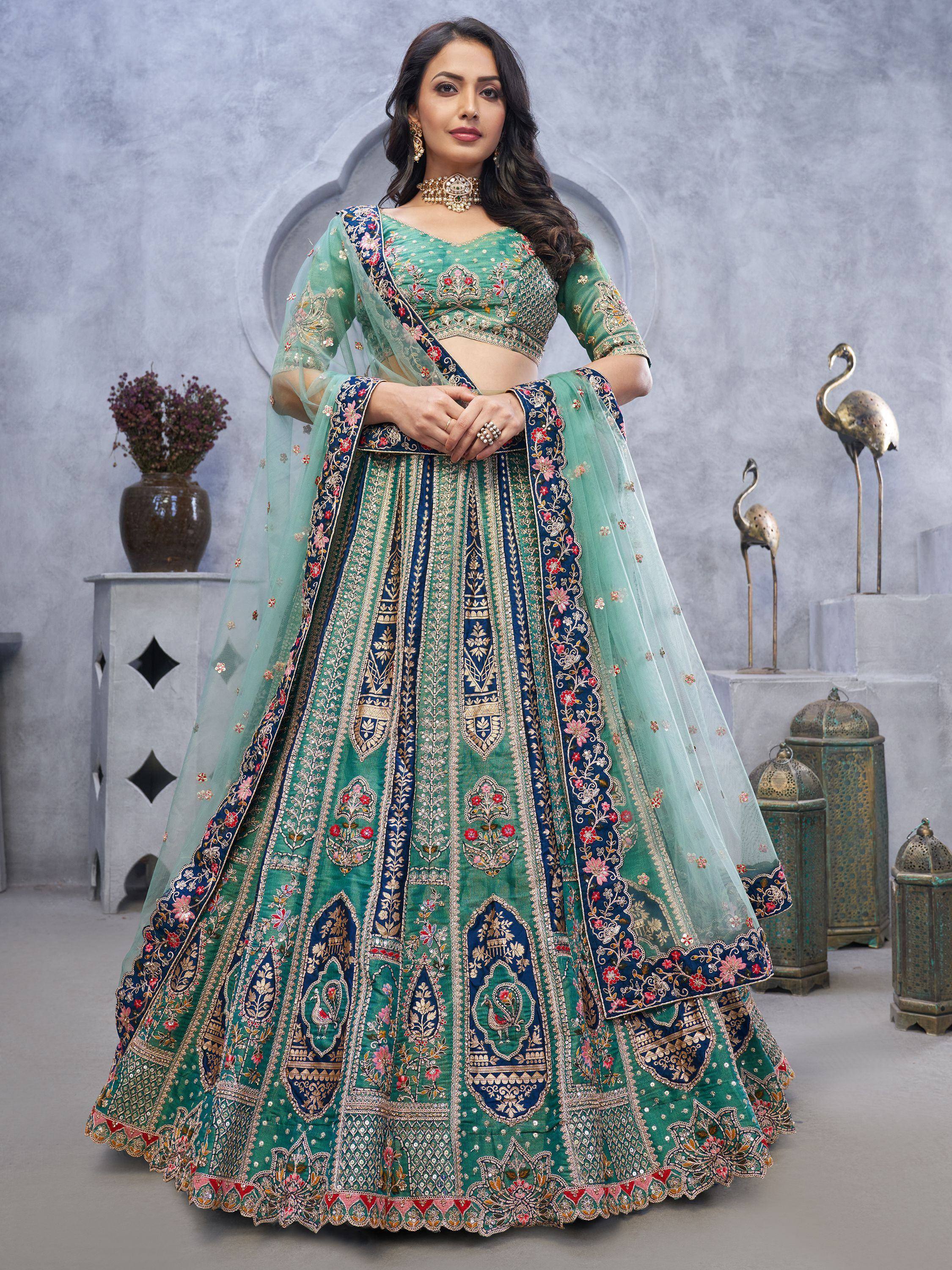 Elegant green and navy blue embroidered lehenga choli with floral motifs and sheer dupatta, perfect for Indian weddings or festive occasions.
