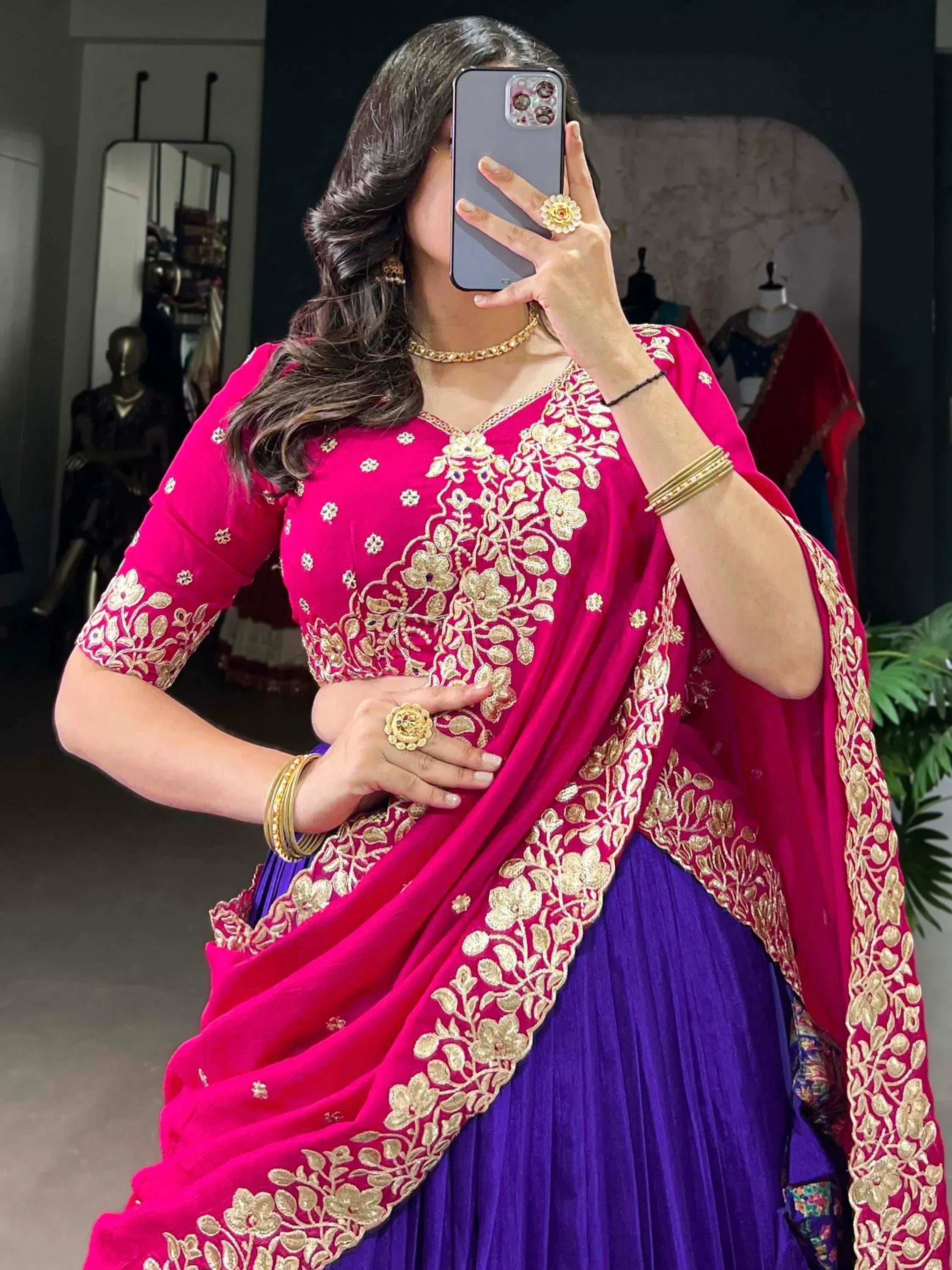Woman in pink and purple Indian ethnic lehenga choli with gold embroidery, taking mirror selfie
