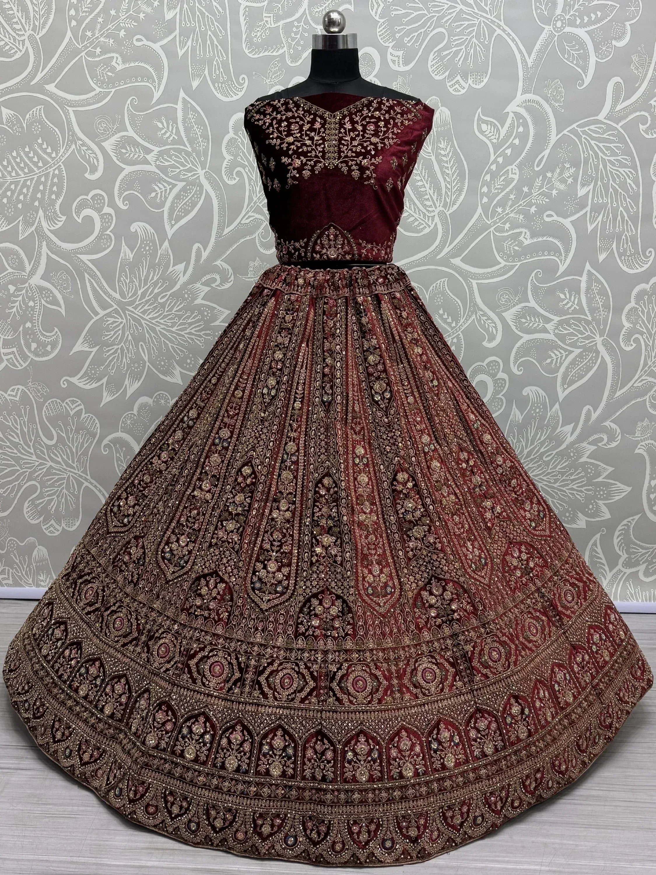 Maroon velvet designer lehenga choli with heavy gold embroidery, perfect for Indian weddings and festive occasions.