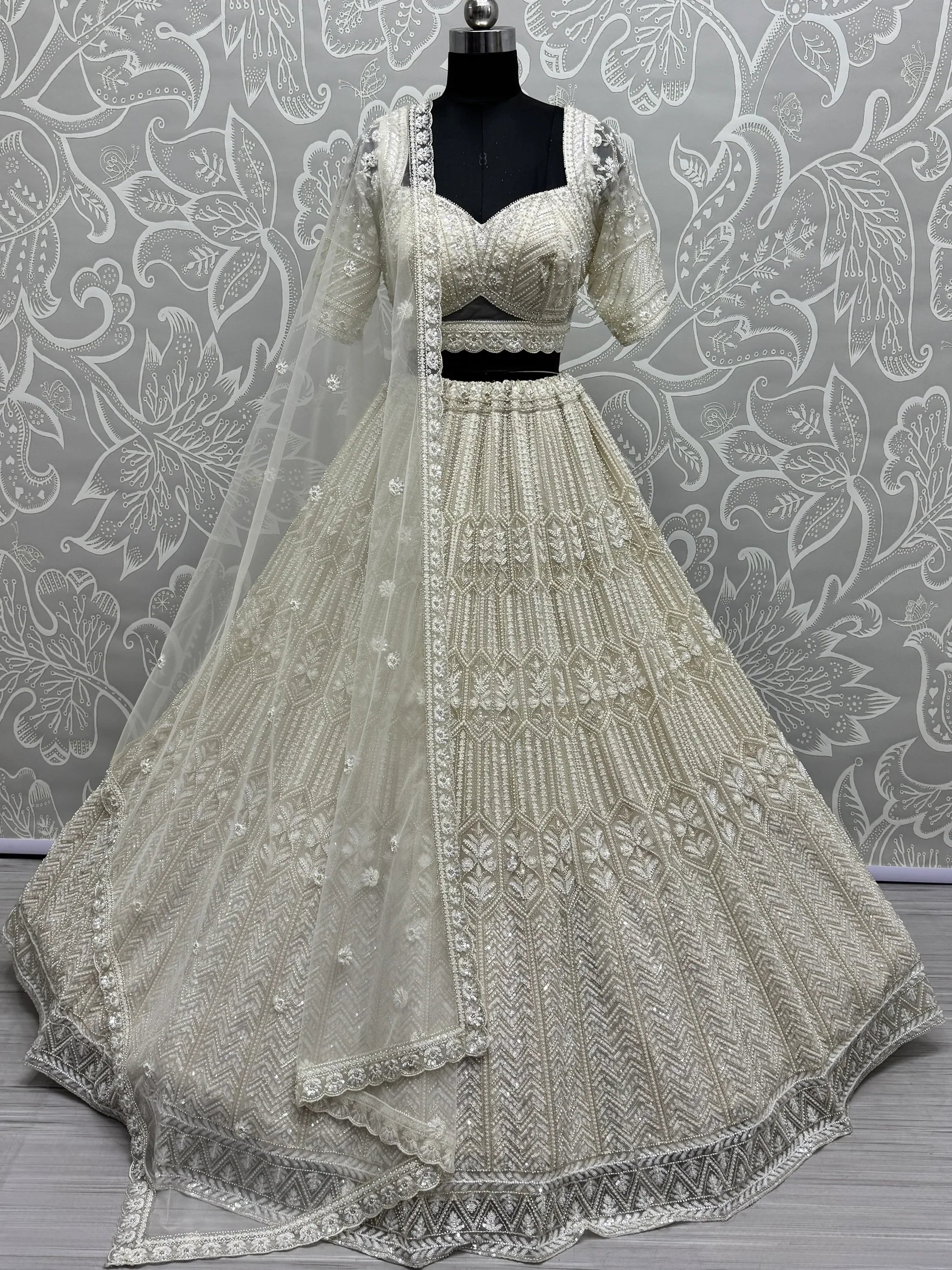 Elegant ivory lehenga choli with heavy embroidery and sheer dupatta, perfect for weddings and festive occasions.