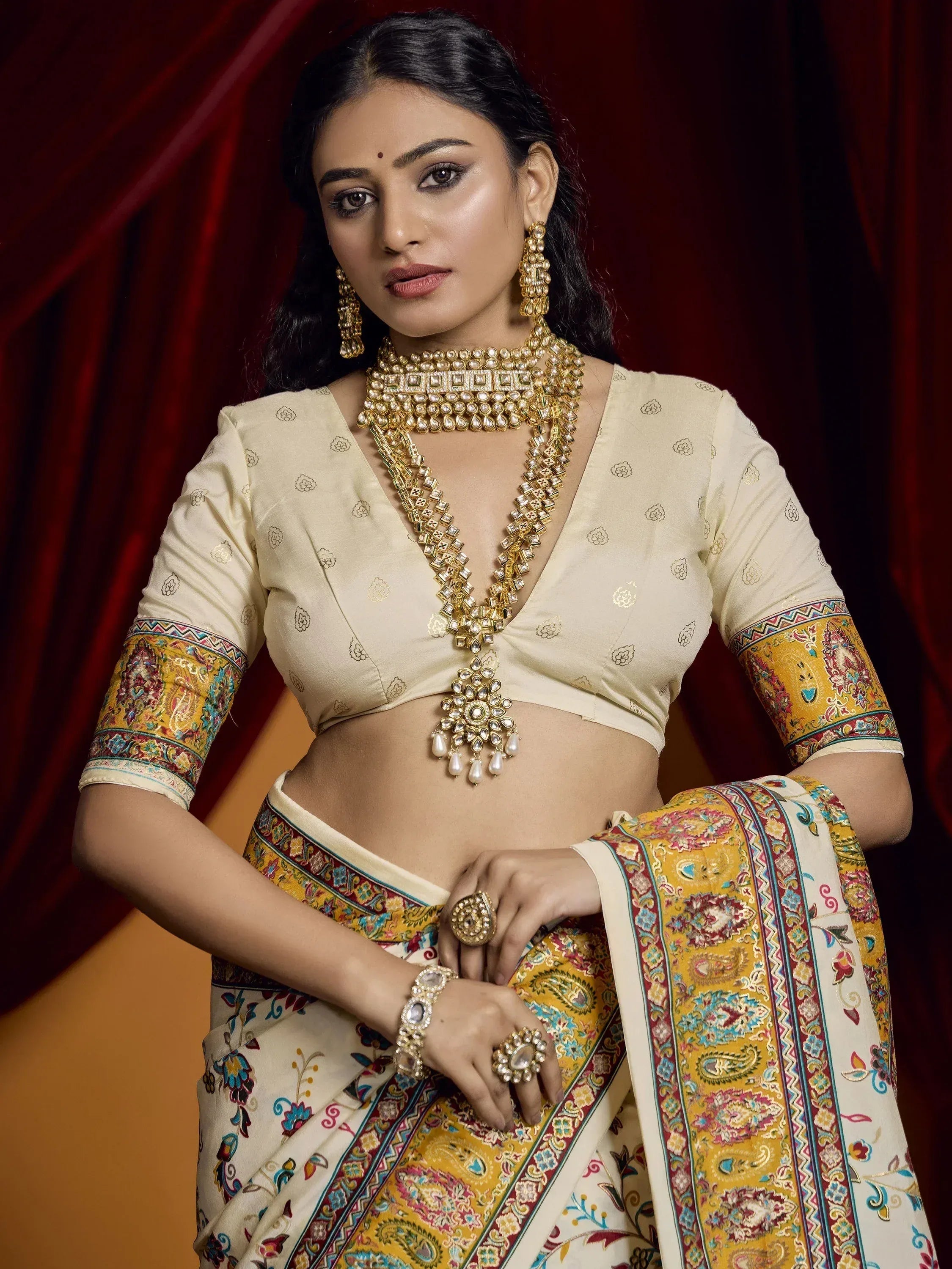 Woman in elegant cream and yellow printed saree with gold jewelry, traditional Indian ethnic wear