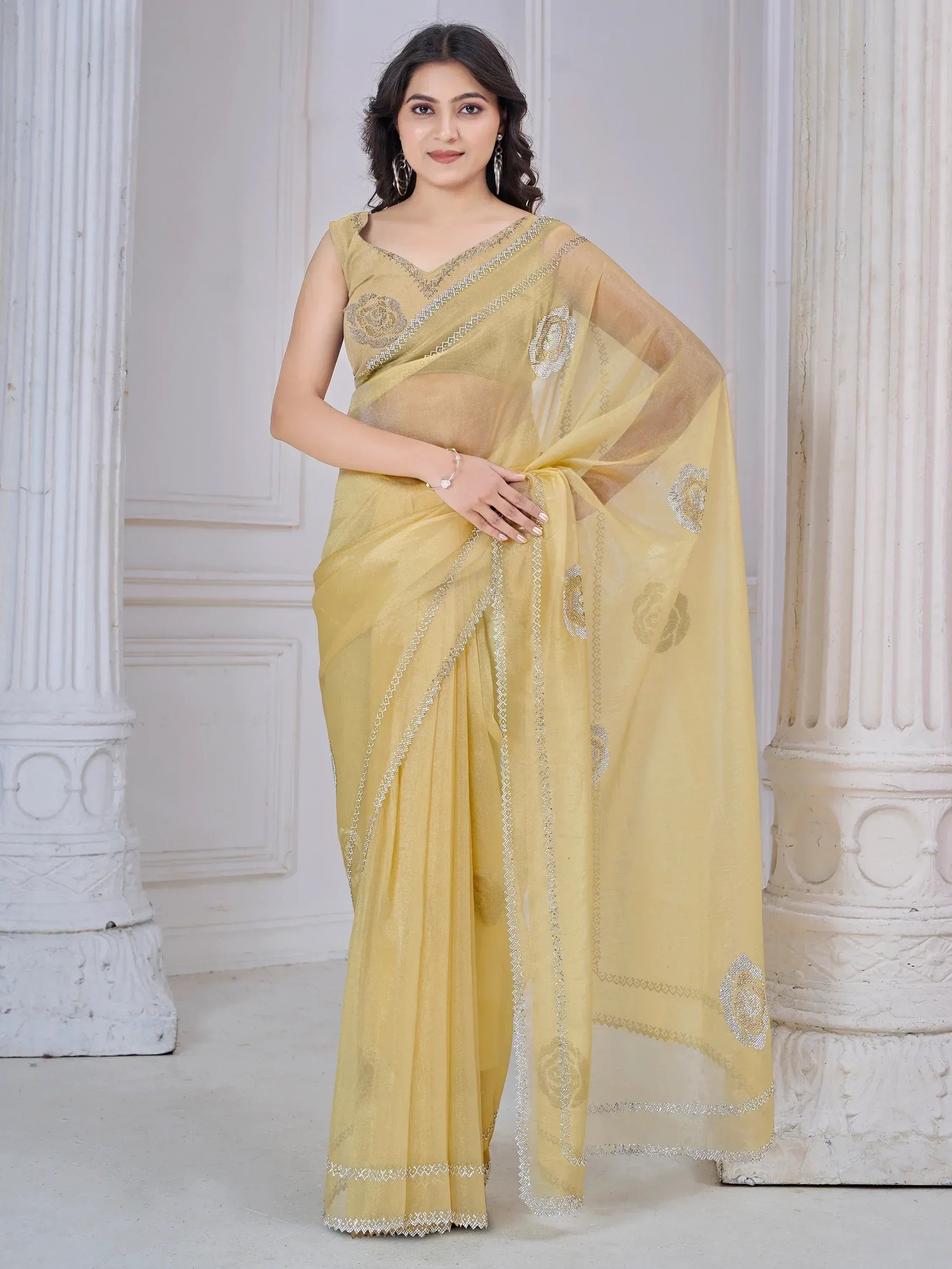 Yellow embroidered saree with floral motifs and silver border, styled with sleeveless blouse for ethnic wear