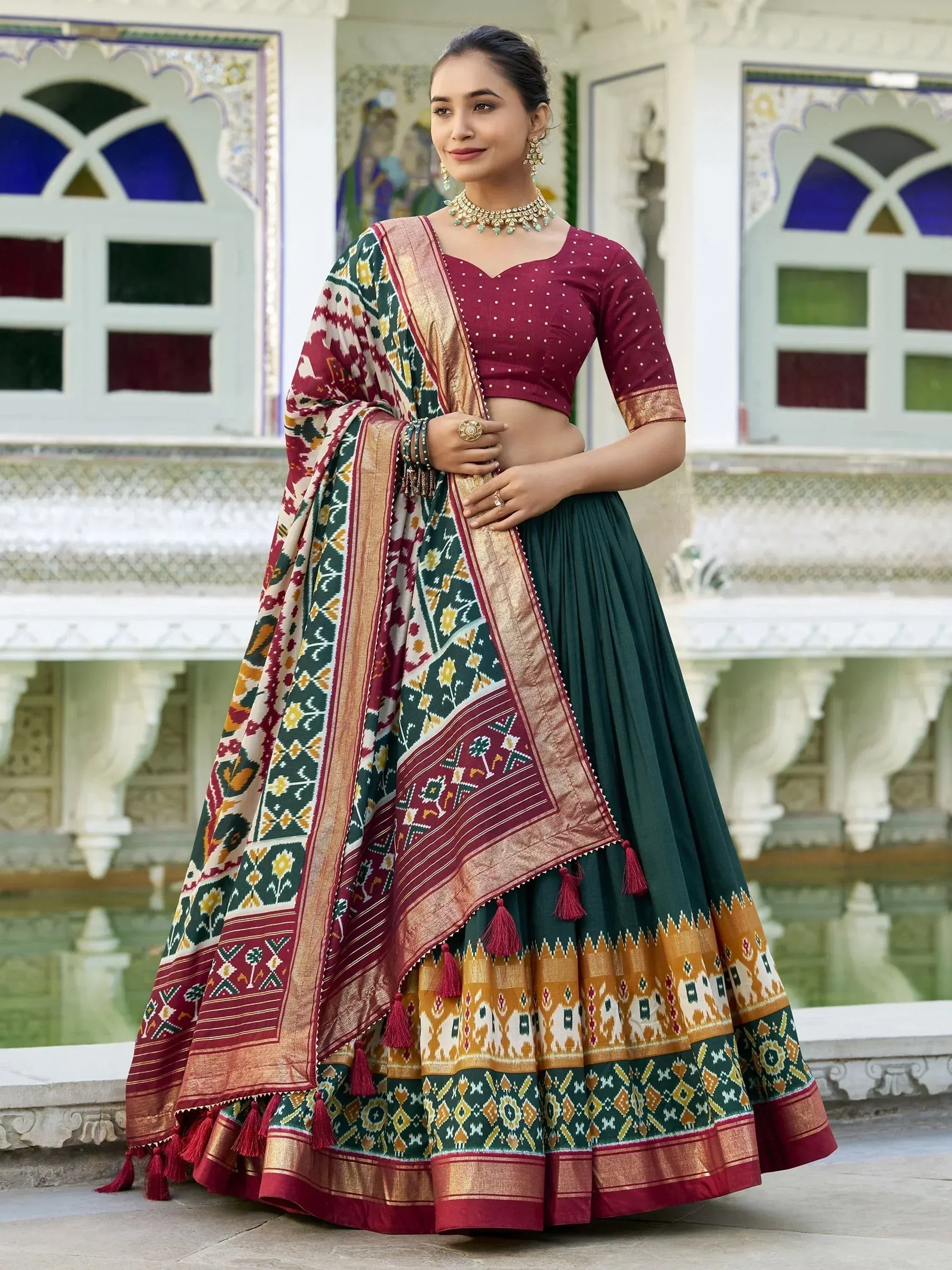 Woman in maroon and green designer lehenga choli with ethnic print and gold border, perfect for Indian weddings