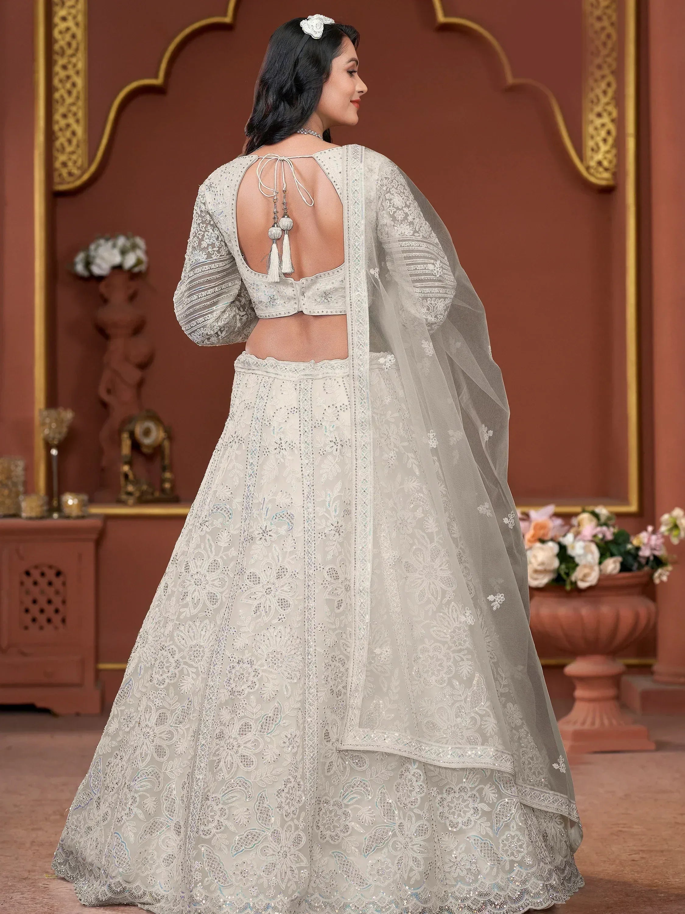 Elegant white embroidered lehenga choli with back tie-up and sheer dupatta, perfect for Indian weddings or festive occasions.