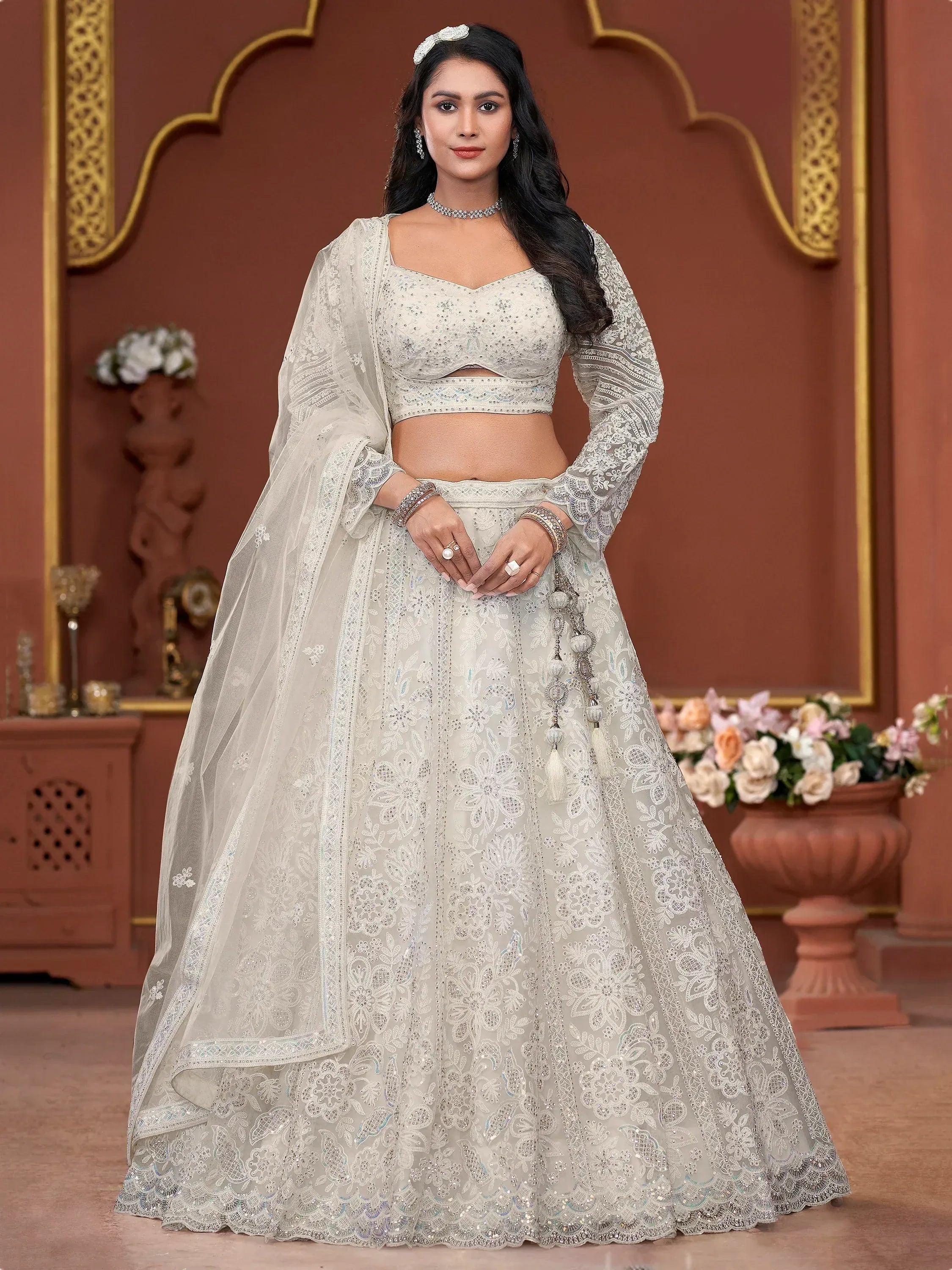 Elegant ivory lehenga choli with intricate embroidery and sheer dupatta, perfect for Indian weddings and festive occasions.