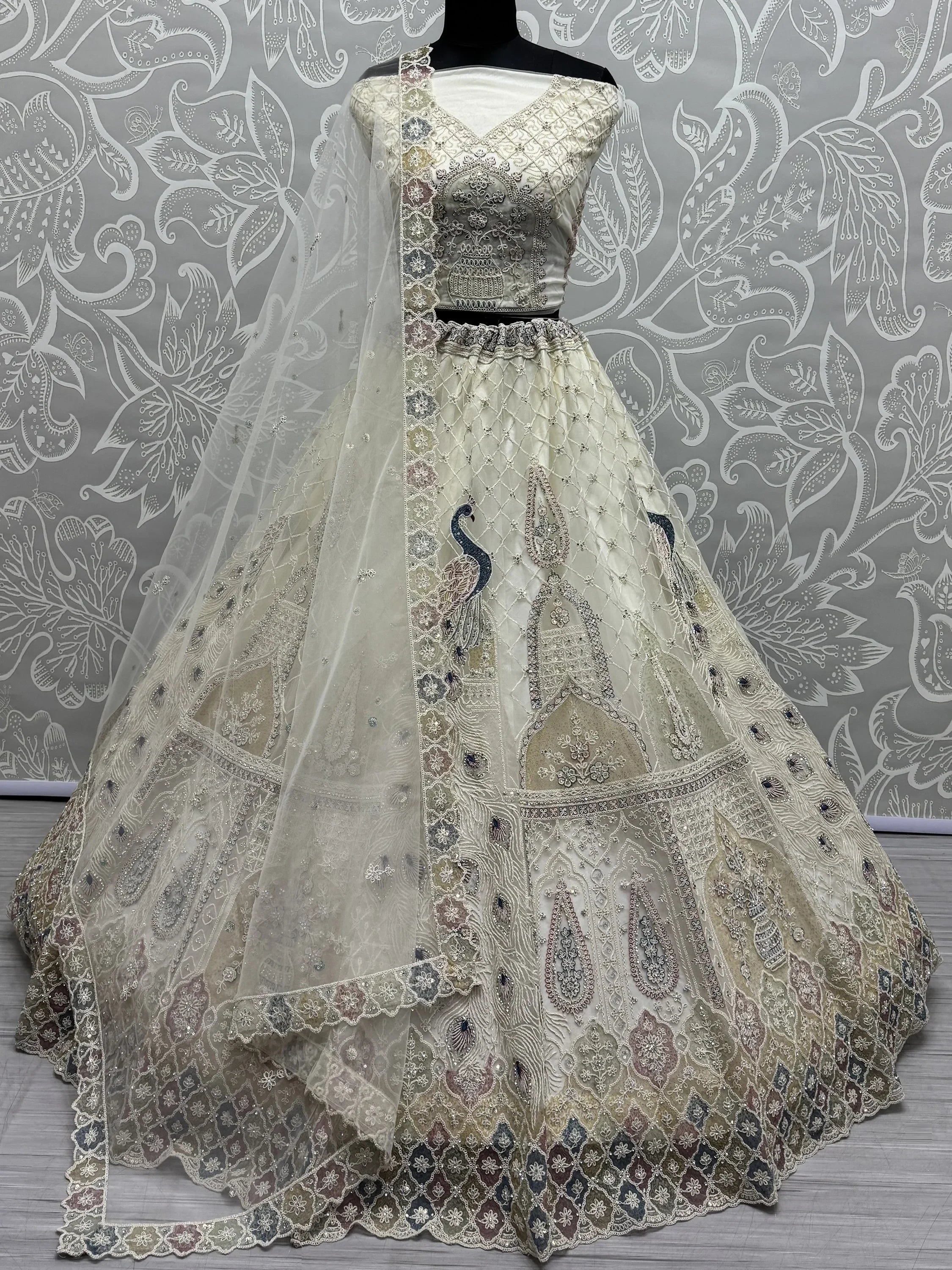 Elegant ivory lehenga choli with peacock embroidery and net dupatta, perfect for Indian weddings and festive occasions.