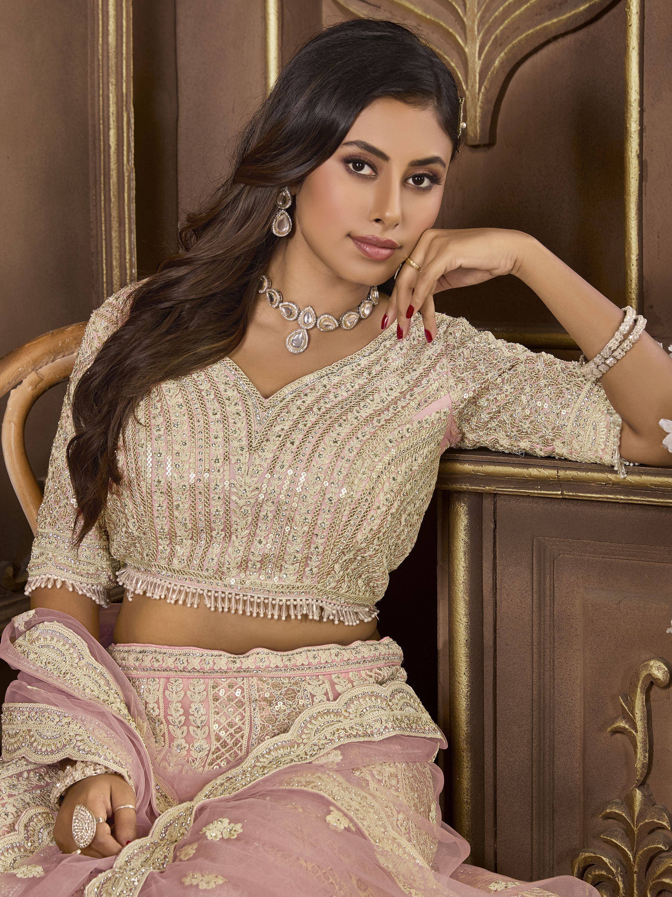 Elegant pink and gold embroidered lehenga choli with detailed embellishments and tassels, perfect for Indian ethnic occasions.