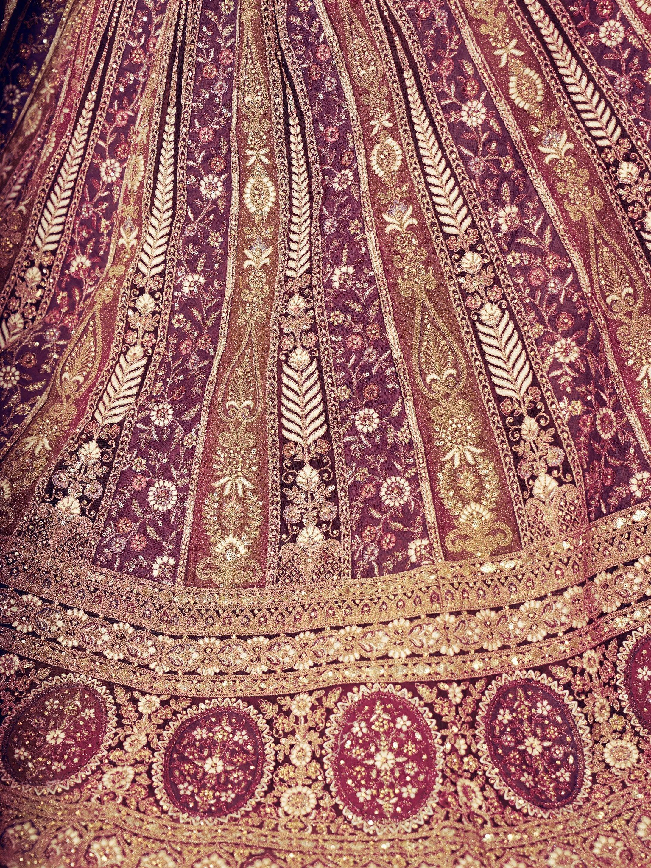 Luxury maroon lehenga with intricate gold embroidery and floral motifs, perfect for Indian weddings.