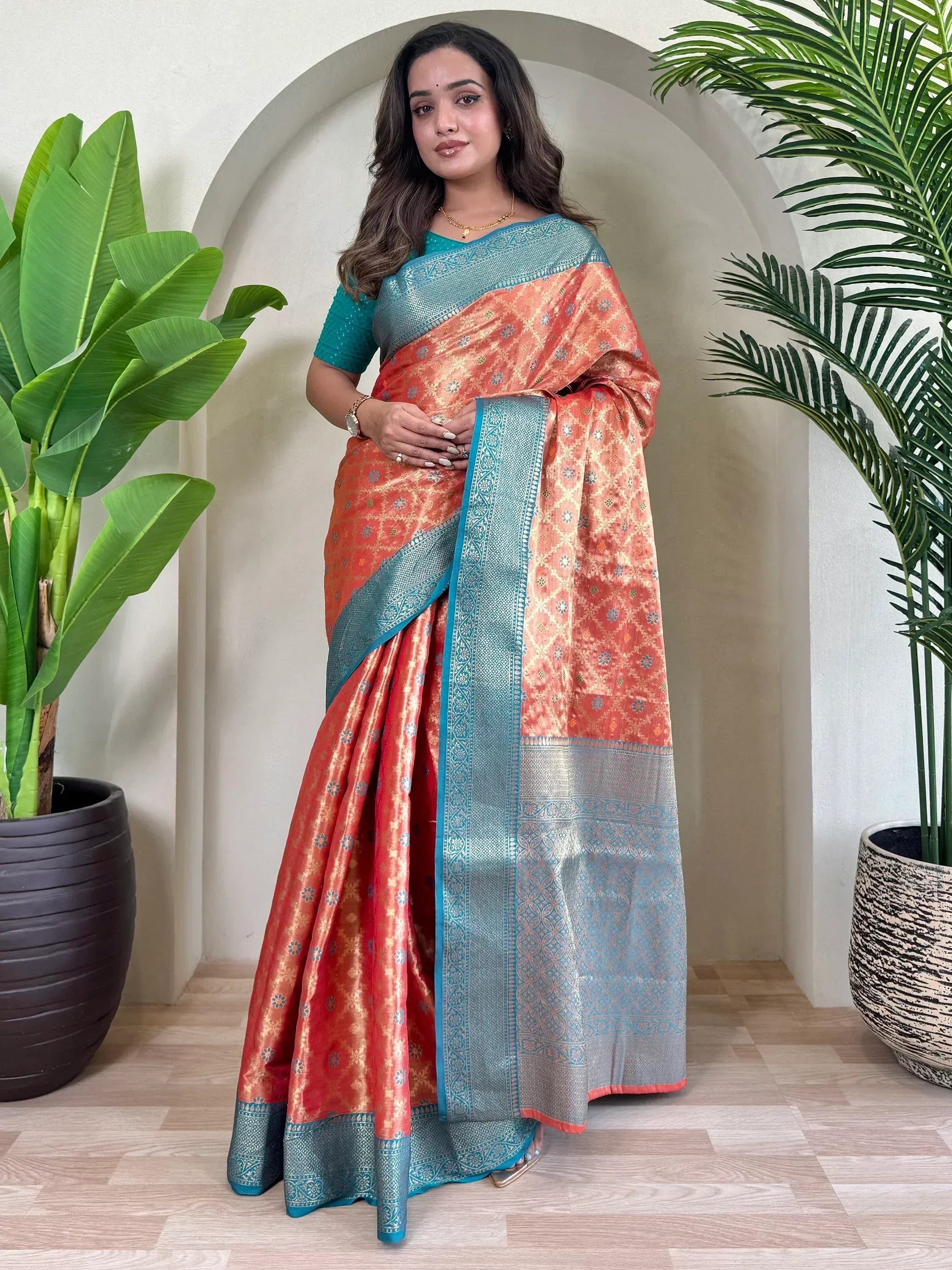 Woman in orange and teal designer saree with intricate patterns, perfect for Indian ethnic wear occasions