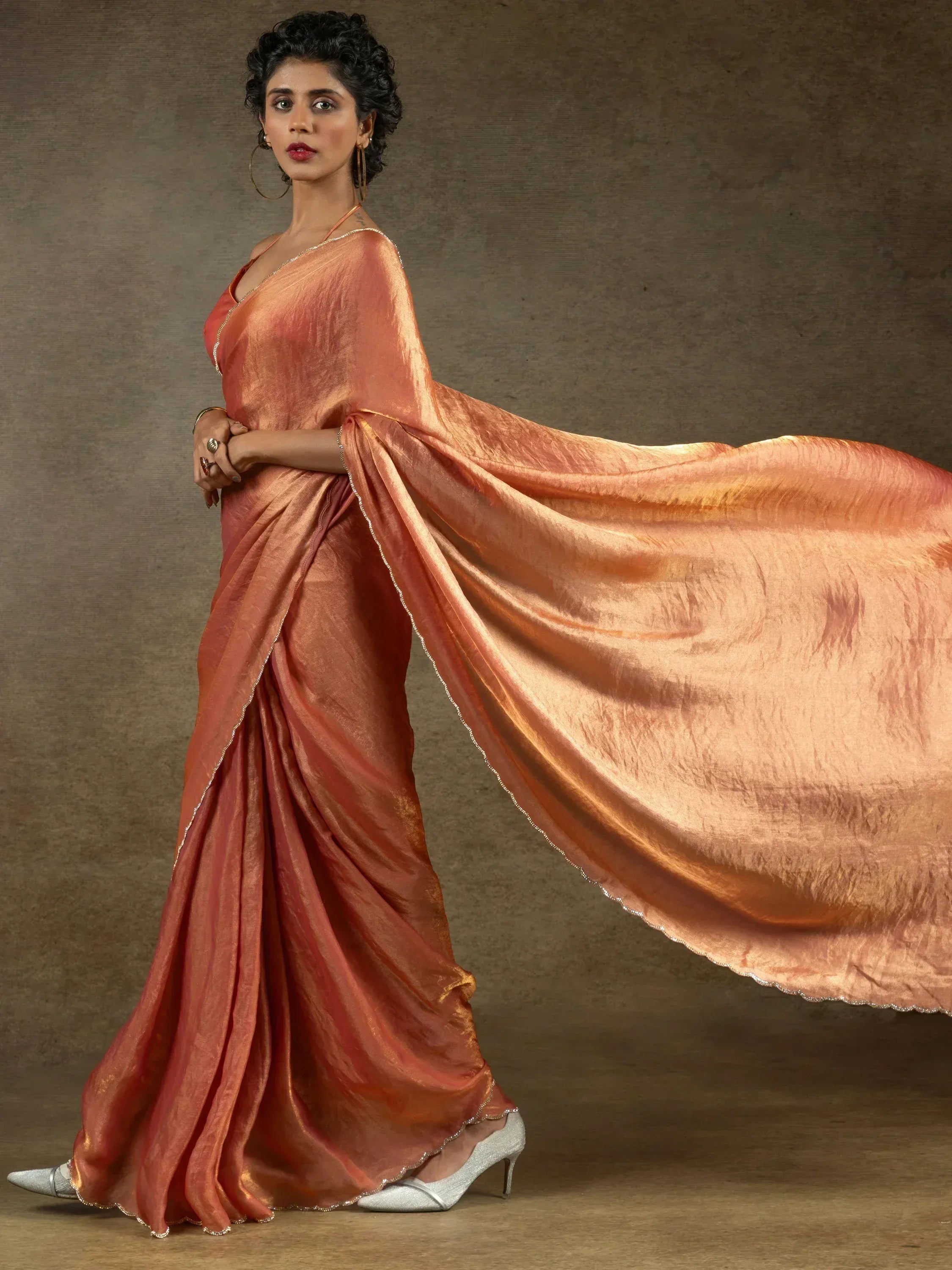 Woman in elegant peach saree with shimmering border, styled for Indian ethnic wear occasions