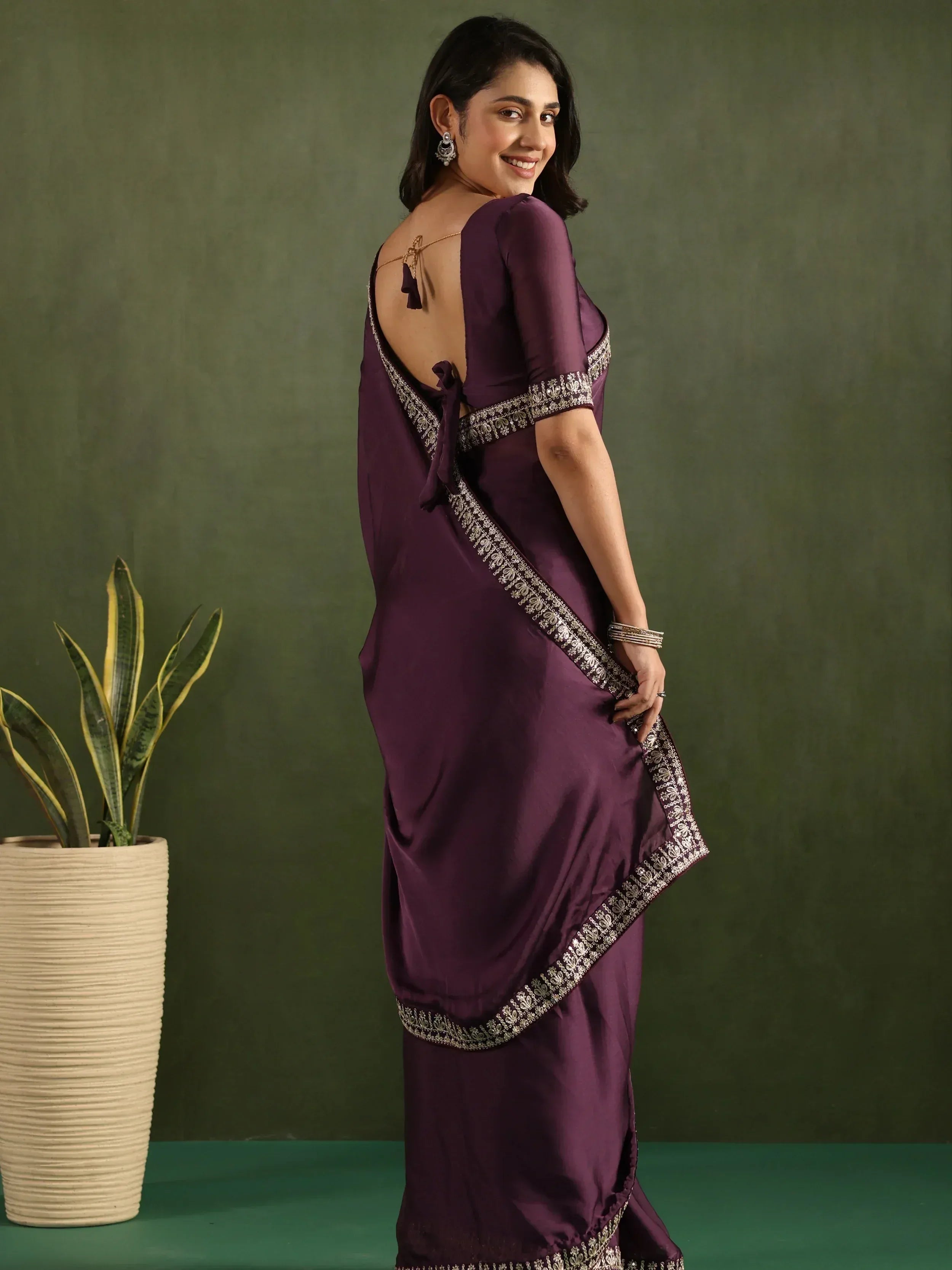 Purple saree with silver embroidery and open back design, styled with traditional earrings and bangles