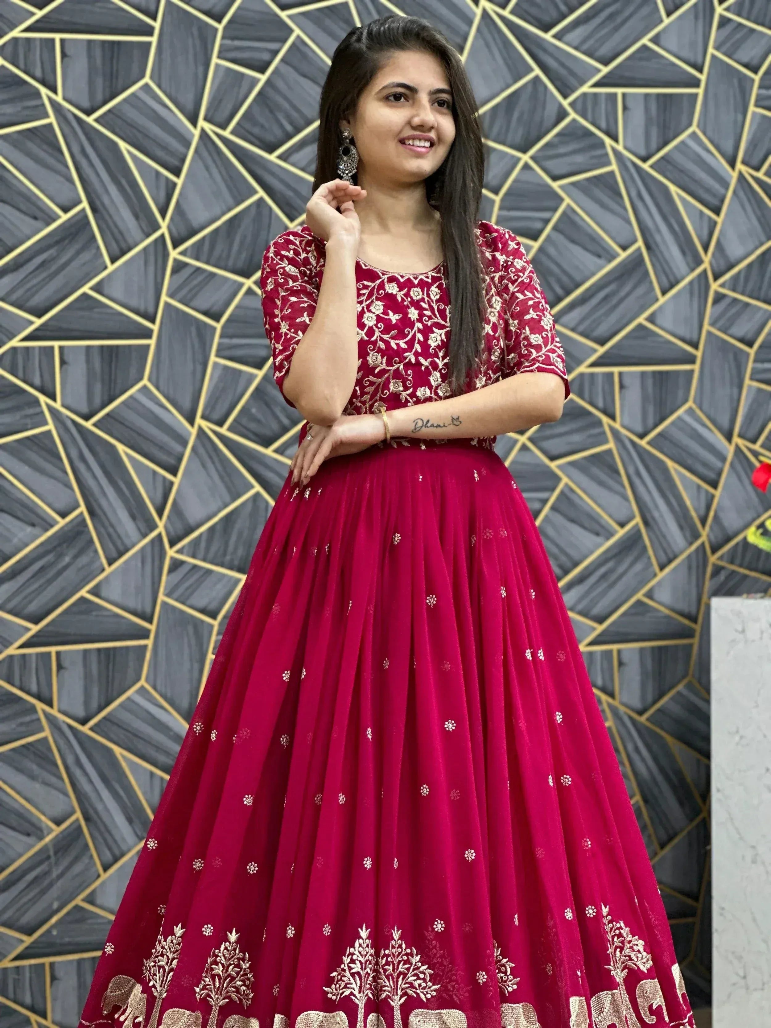Woman in maroon embroidered lehenga choli with gold floral and elephant motifs, perfect for Indian ethnic occasions.