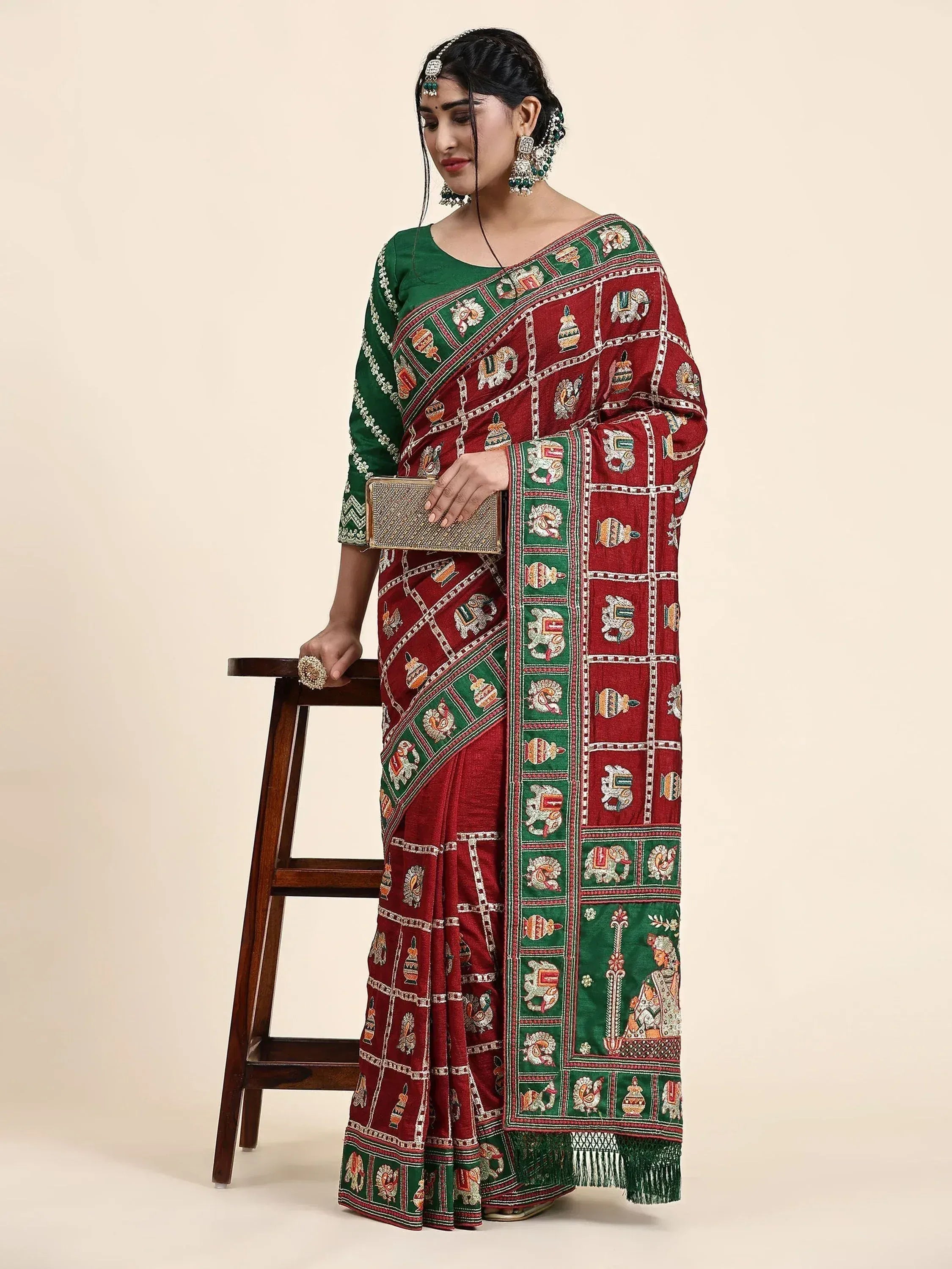 Woman in maroon and green embroidered saree with elephant motifs, traditional Indian ethnic wear