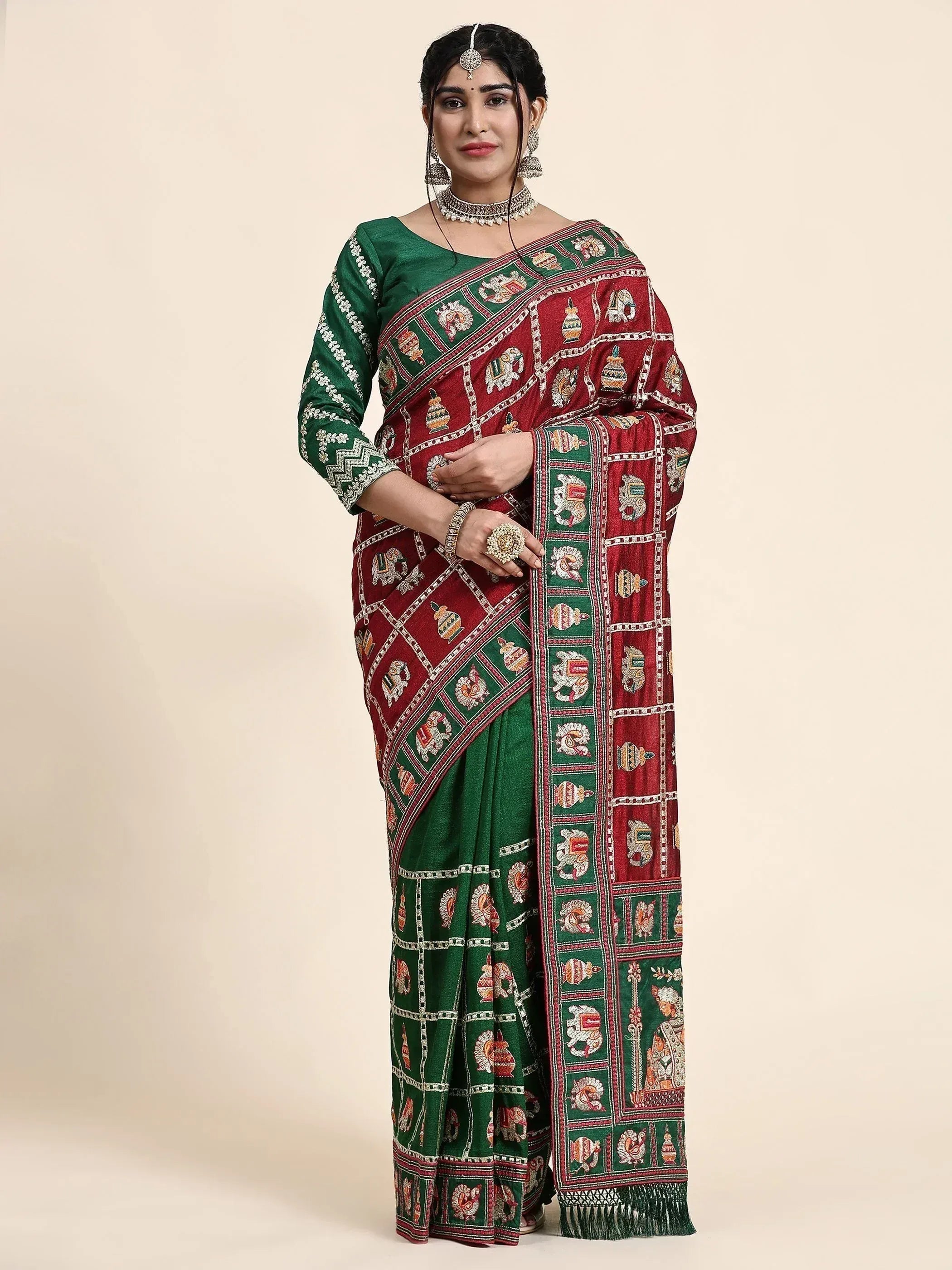 Woman in red and green ethnic saree with elephant and pot motifs, perfect for Indian festive occasions.