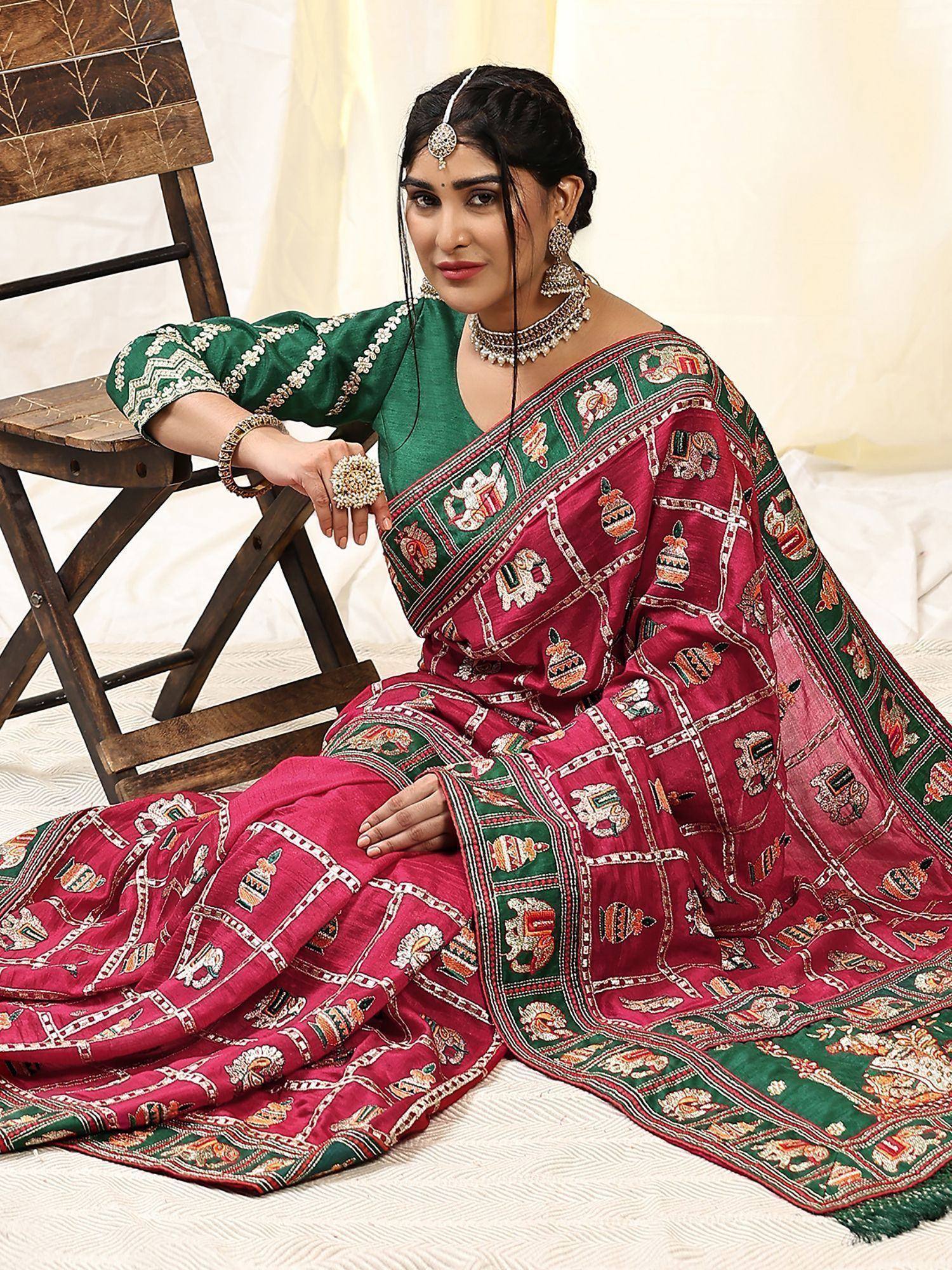 Woman in maroon and green embroidered saree with elephant motifs, styled with traditional jewelry for ethnic wear.