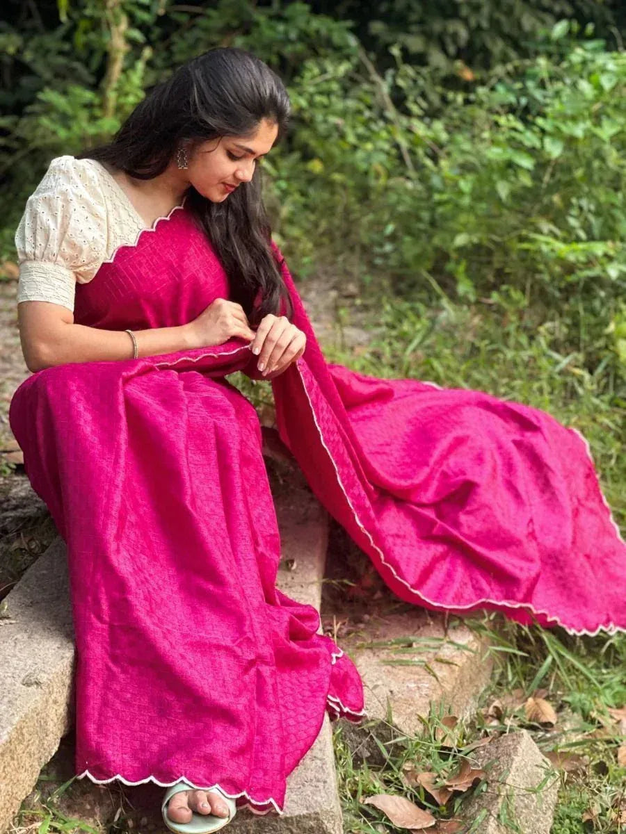 Woman in vibrant pink ethnic gown with white scalloped blouse, sitting outdoors on stone steps