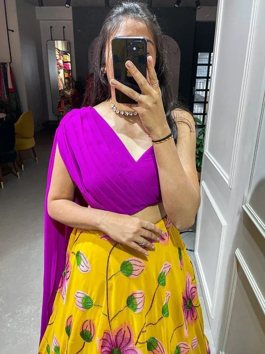 Woman in vibrant purple and yellow floral lehenga choli, mirror selfie at boutique