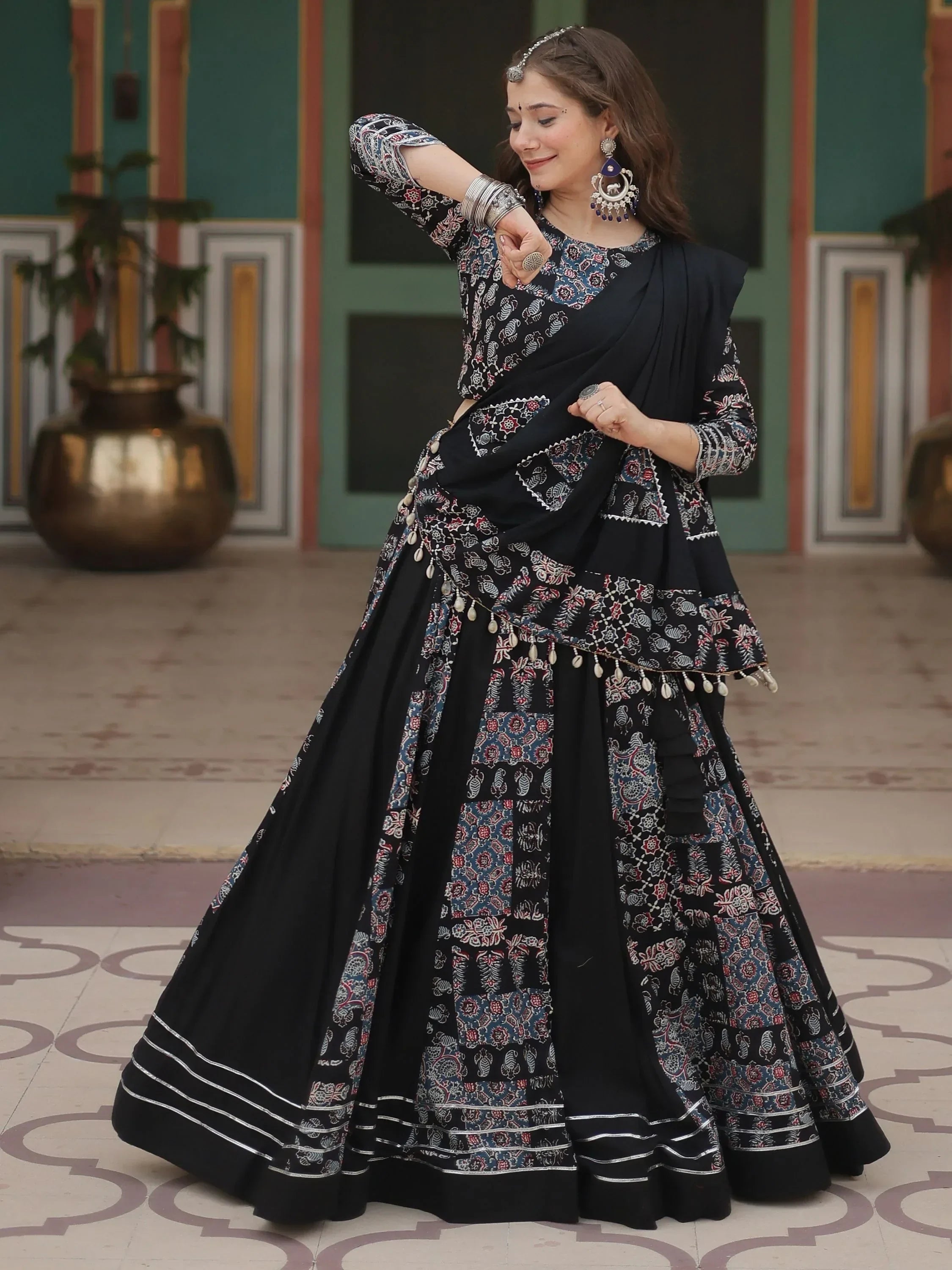 Woman in black printed lehenga choli with ethnic jewelry, perfect for Indian weddings or festive occasions.