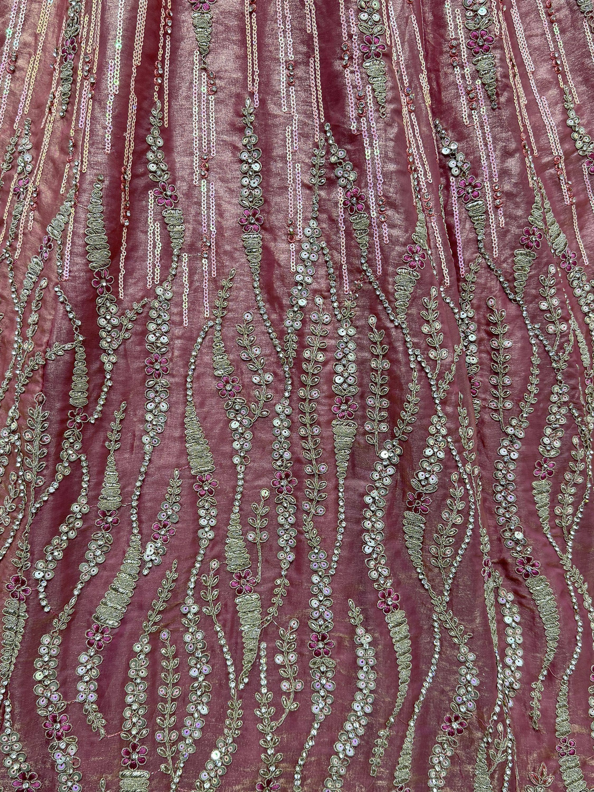 Luxury maroon ethnic wear fabric with intricate gold embroidery, sequins, and floral motifs for lehenga or saree.