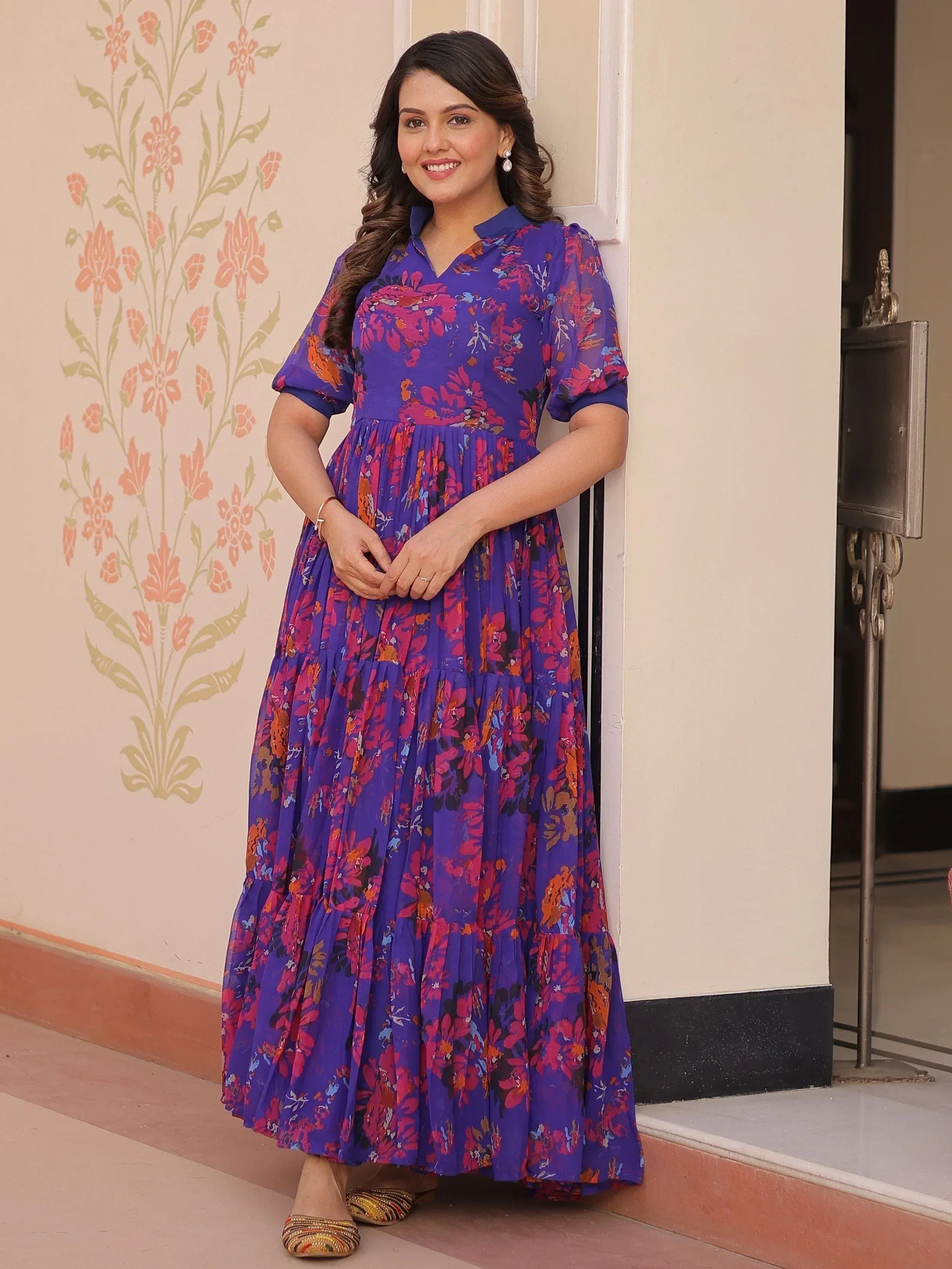 Woman in purple floral ethnic gown with tiered skirt, perfect for Indian occasions and festive wear.