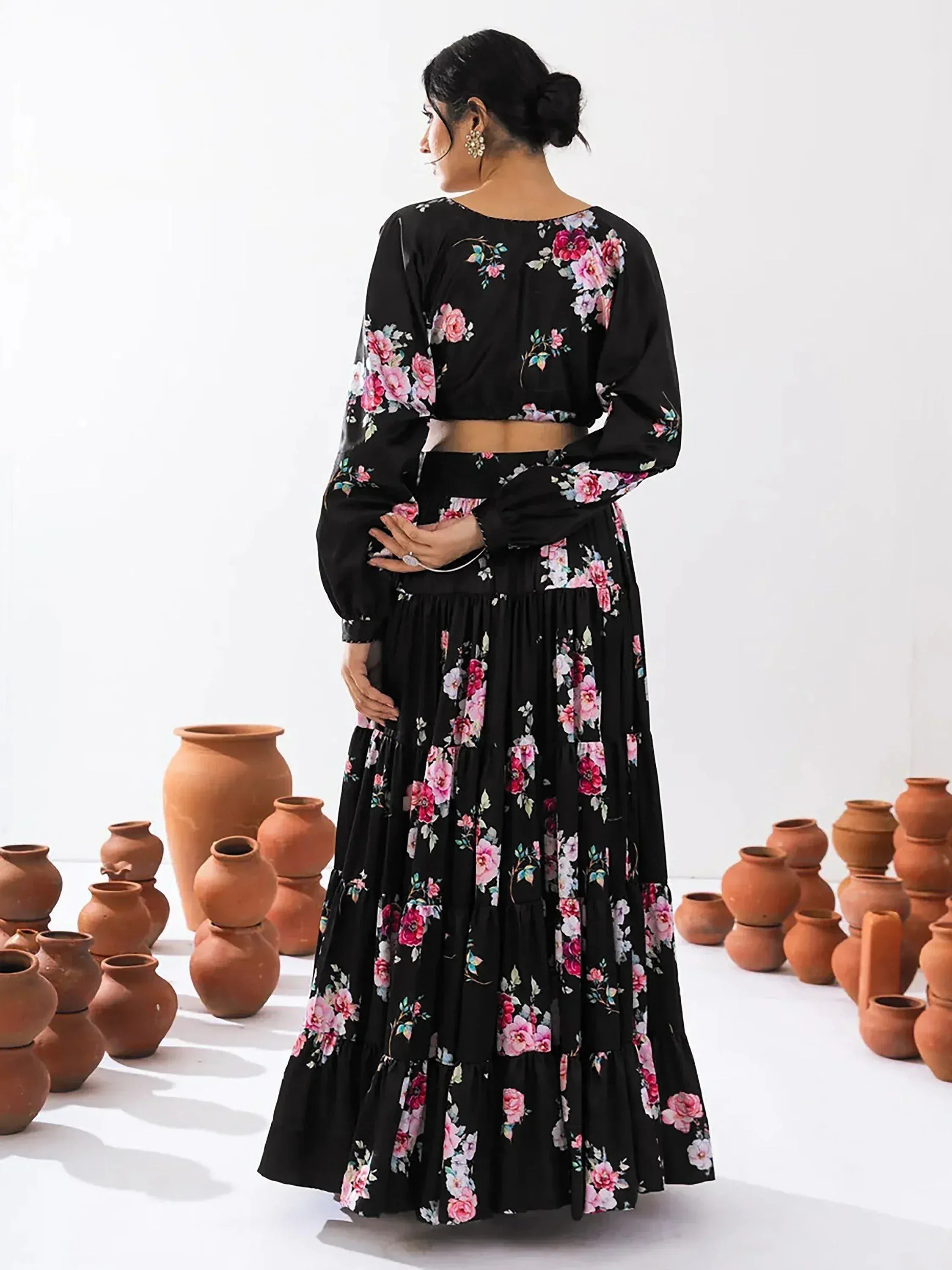 Black floral print ethnic gown with long sleeves and tiered skirt, styled with clay pots
