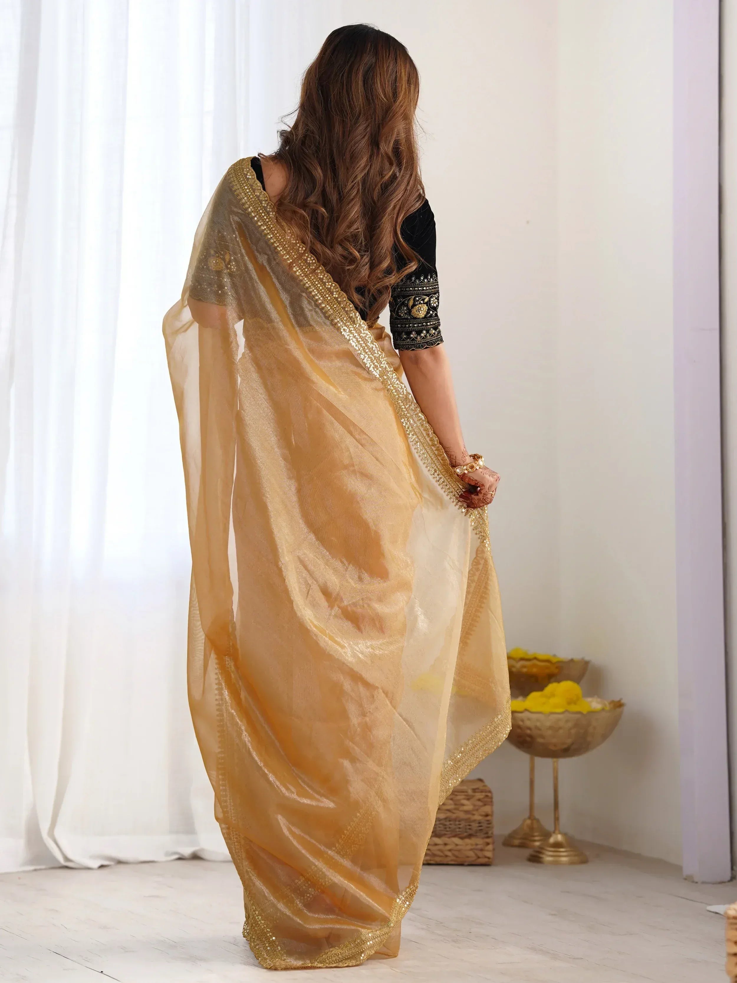 Elegant gold saree with sequin border paired with black embroidered blouse, perfect for Indian ethnic occasions.