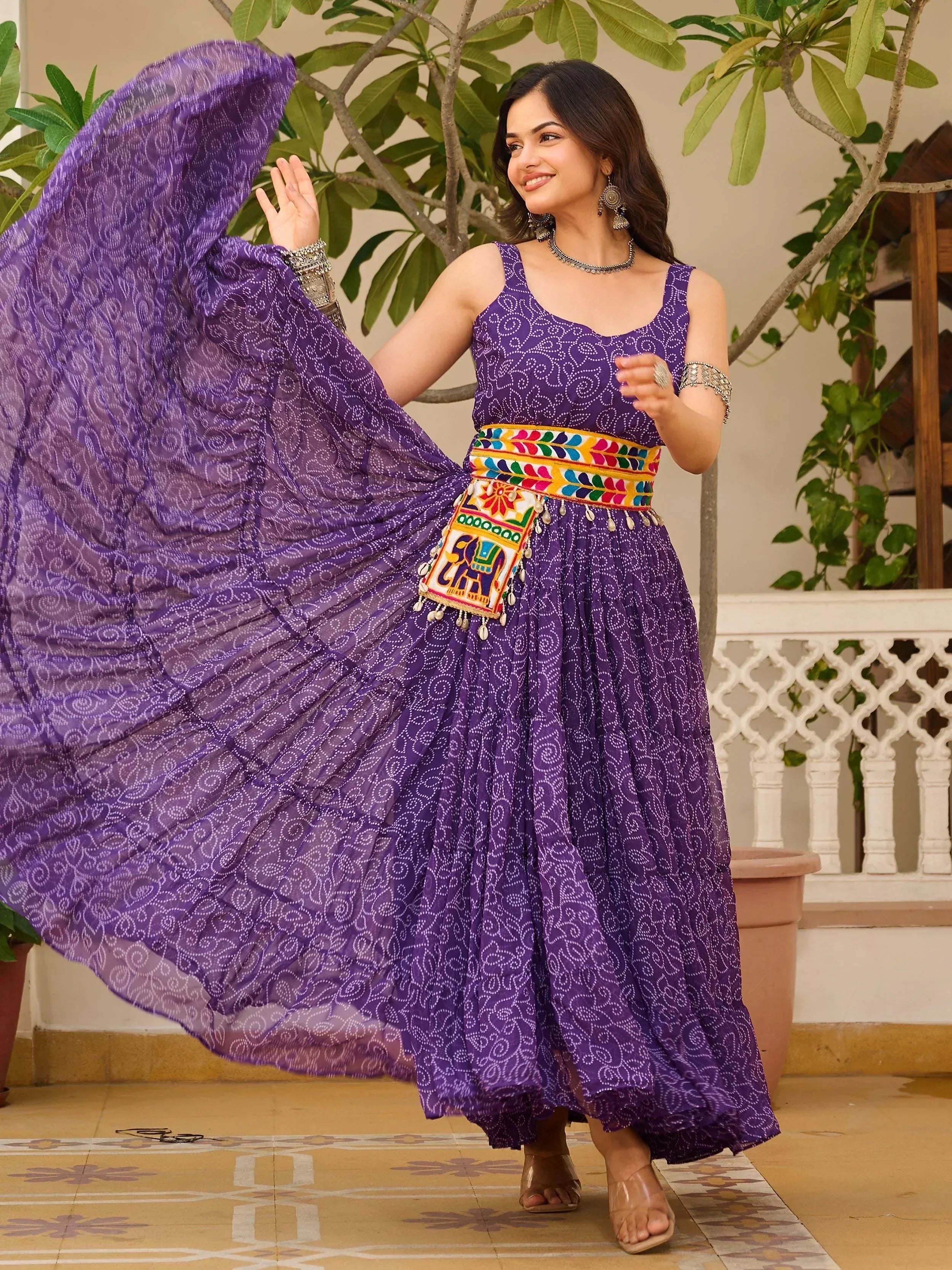 Purple ethnic gown with printed patterns and colorful embroidered belt, perfect for Indian festive occasions.