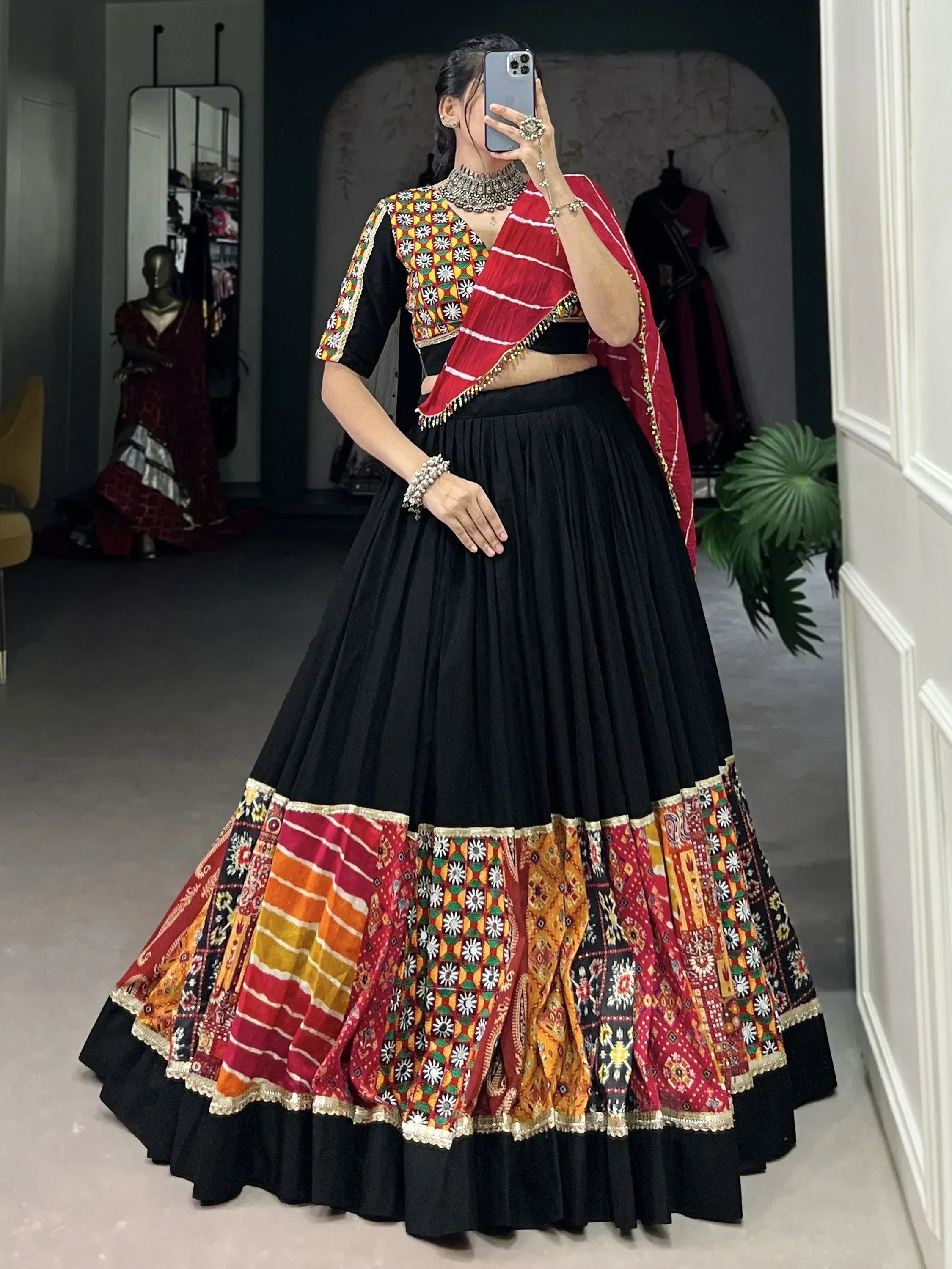 Black lehenga with colorful embroidered border, red dupatta, and mirror work blouse for Indian ethnic wear