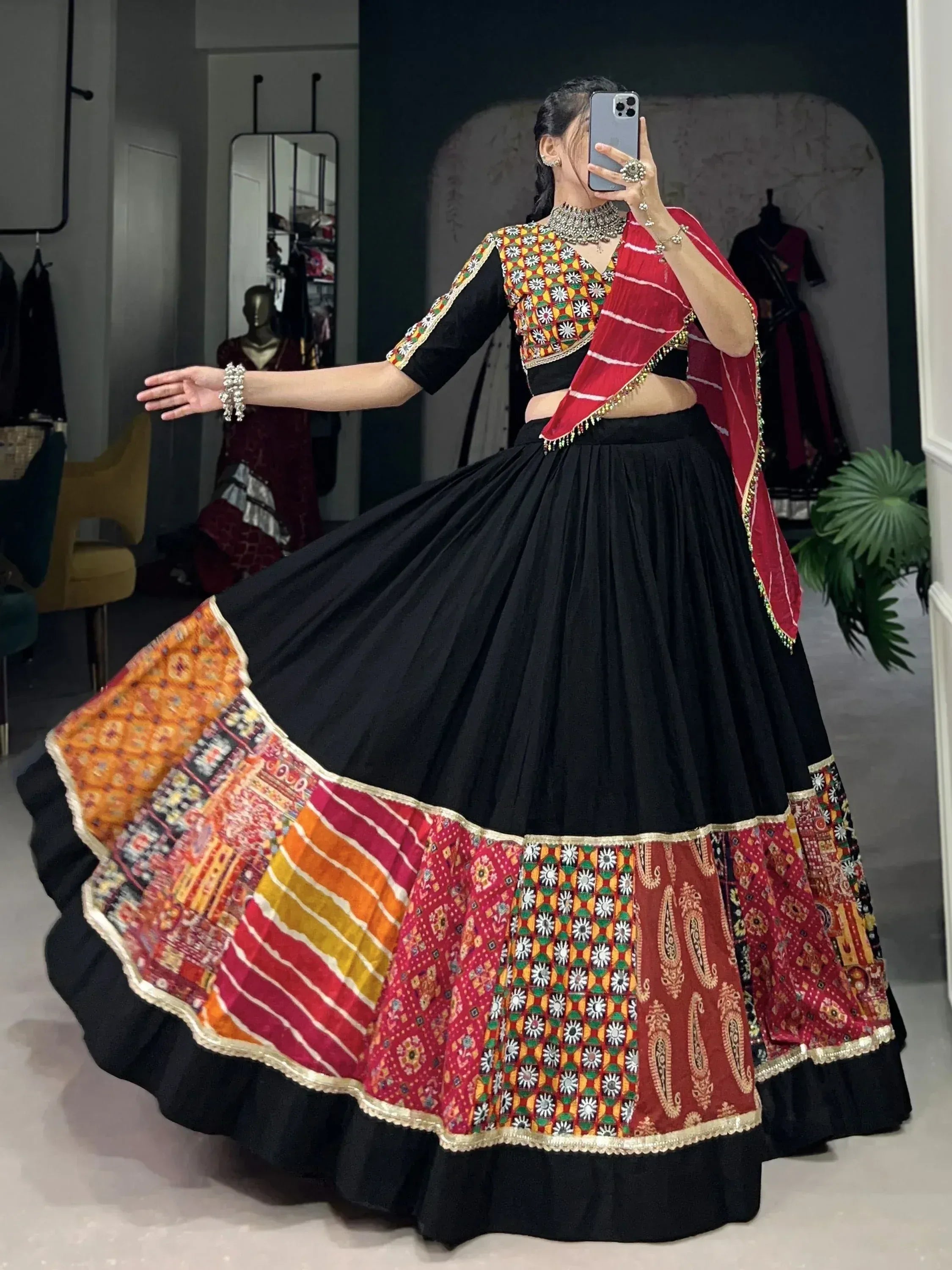 Black lehenga with colorful embroidered border and matching choli, styled with red dupatta for Indian ethnic wear