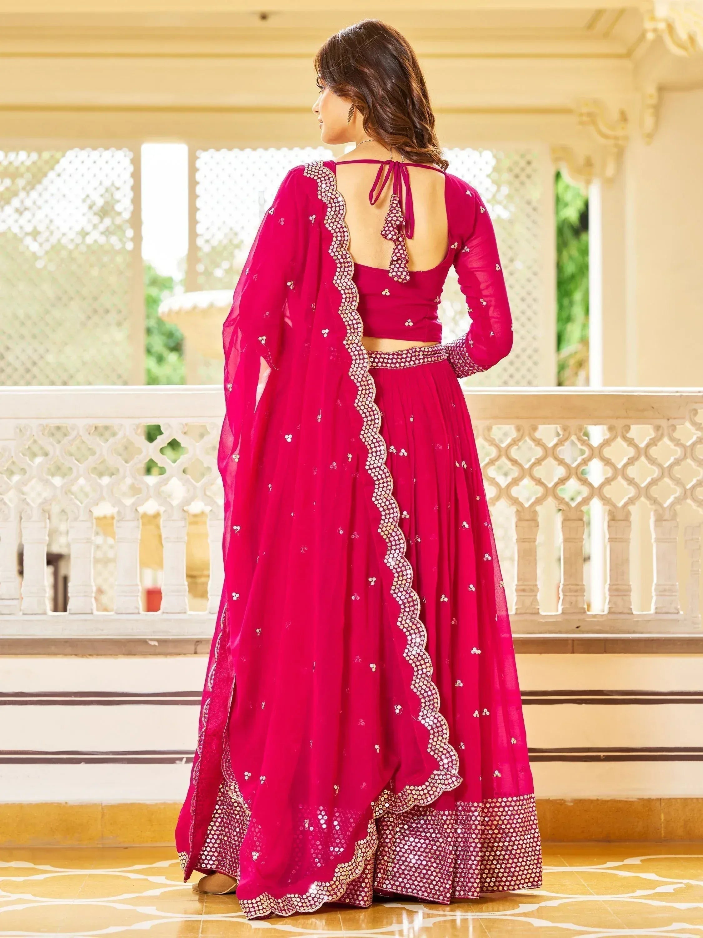Fuchsia pink designer lehenga choli with sequin embroidery, back view on balcony