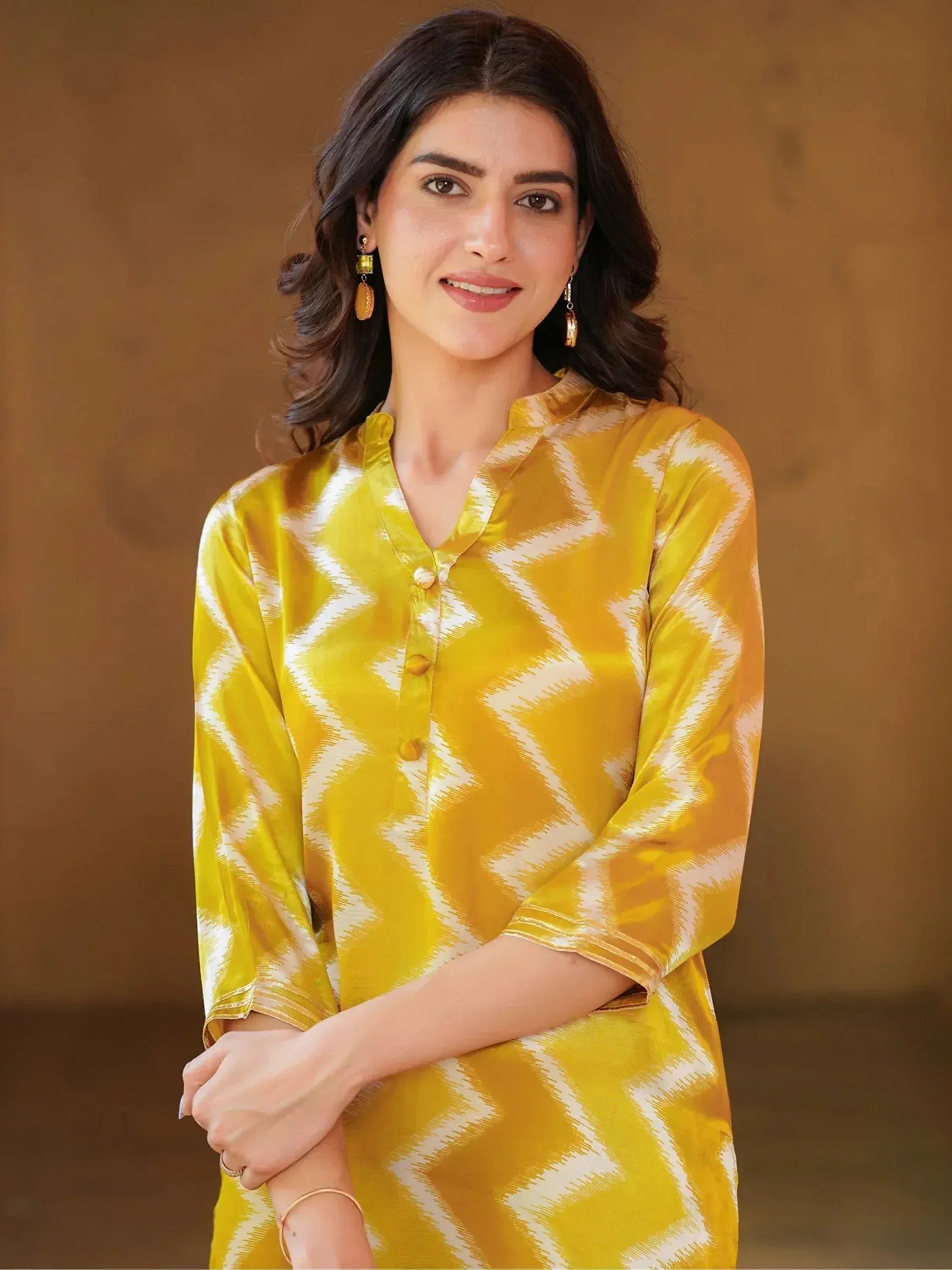 Yellow and white ikat print ethnic kurta with button front, styled with gold earrings for festive wear
