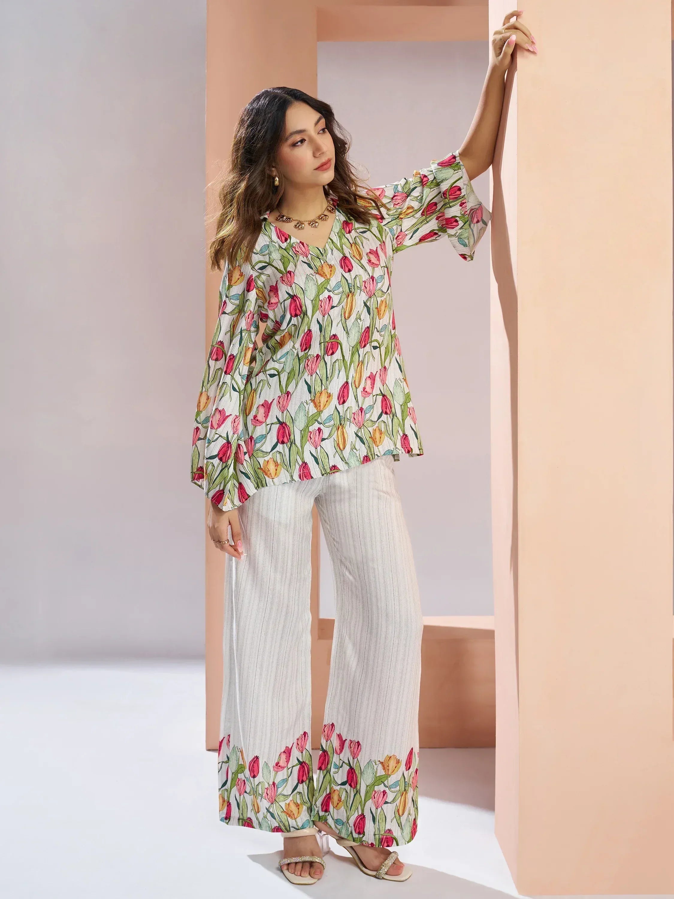 Woman in a floral print kurti and palazzo set with bell sleeves and white base.