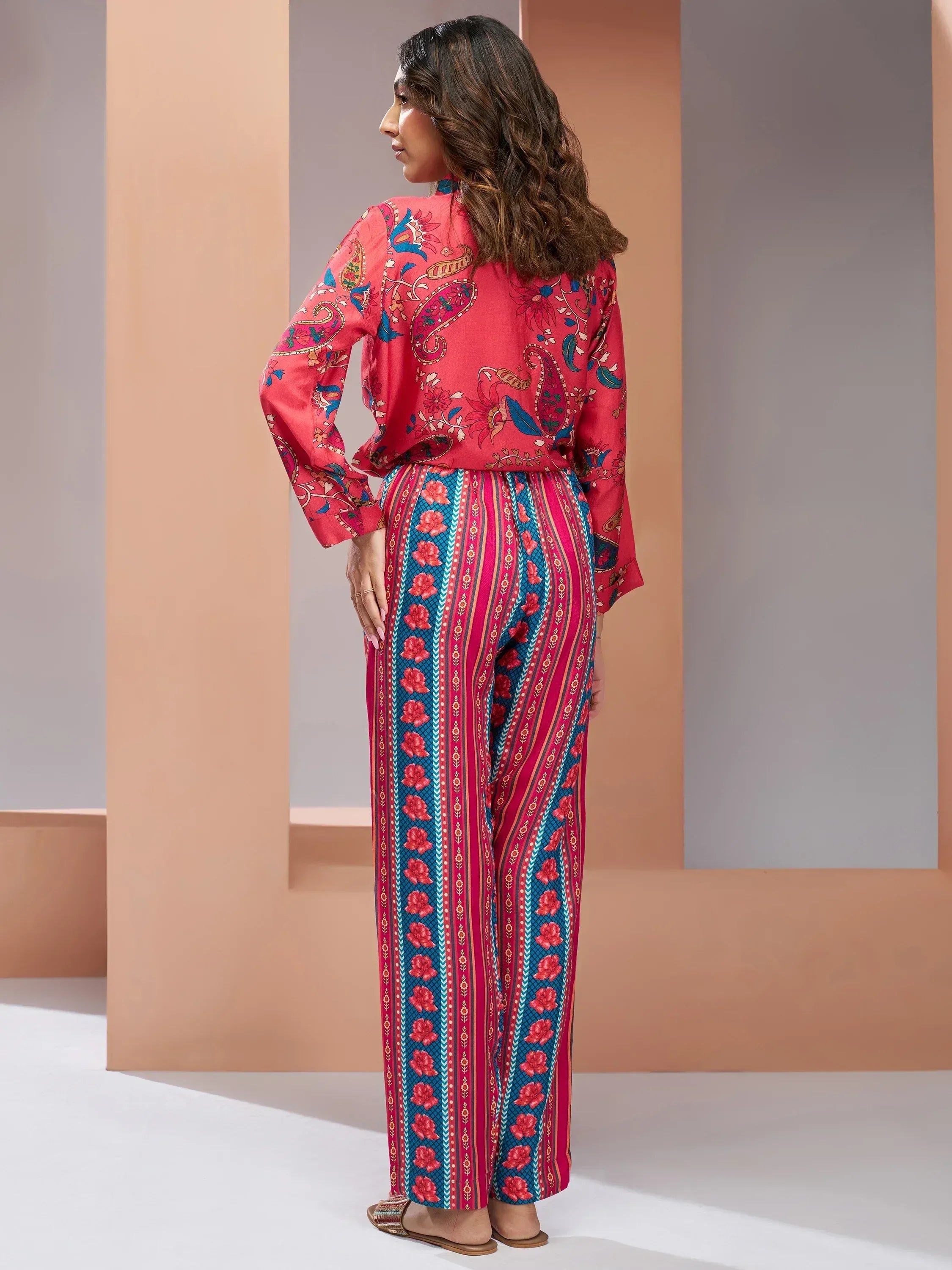 Woman in vibrant red and blue printed ethnic salwar kameez with paisley and floral patterns, stylish Indian wear