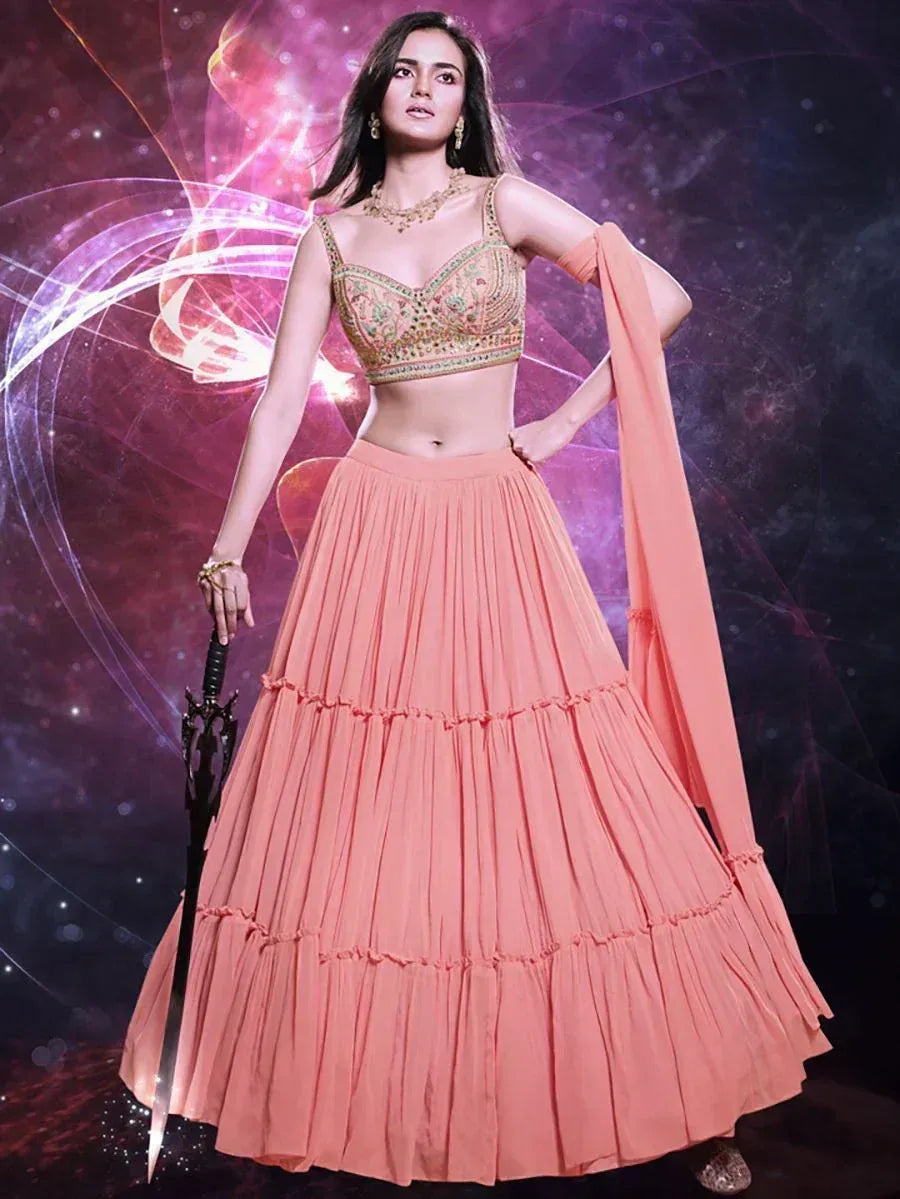 Peach lehenga choli with embroidered blouse, pleated skirt, and dupatta, styled for festive occasions