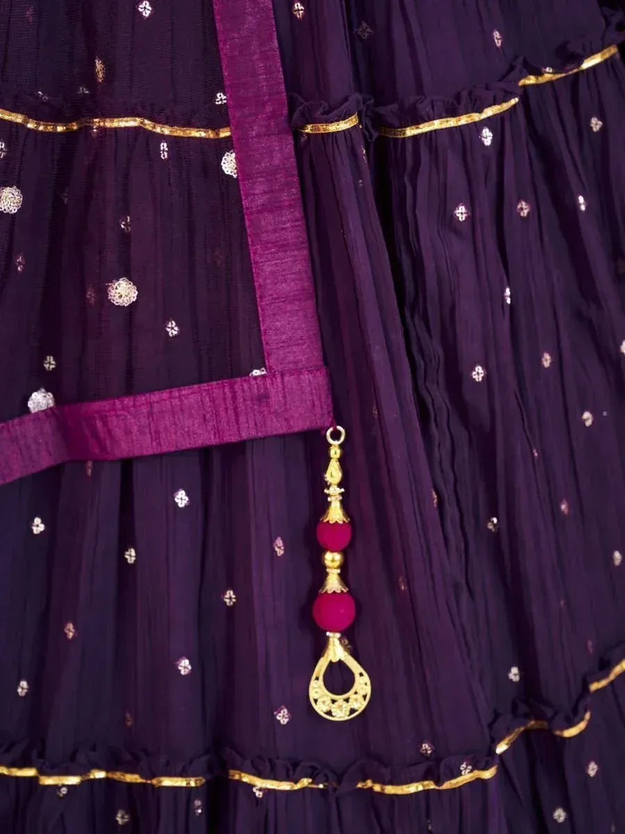 Purple ethnic lehenga with gold embroidery, pleated layers, and decorative tassel for Indian weddings