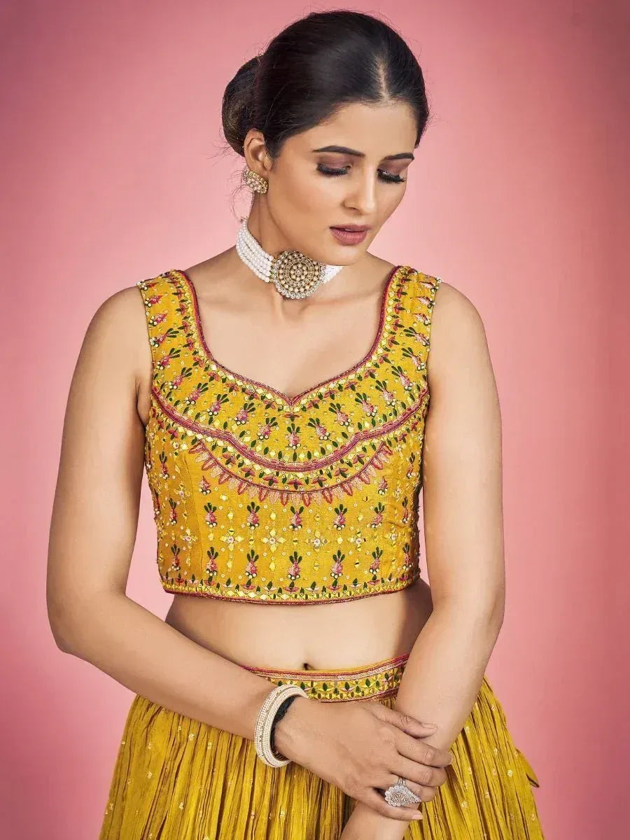 Yellow embroidered lehenga choli with floral motifs and pearl jewelry, perfect for Indian ethnic occasions