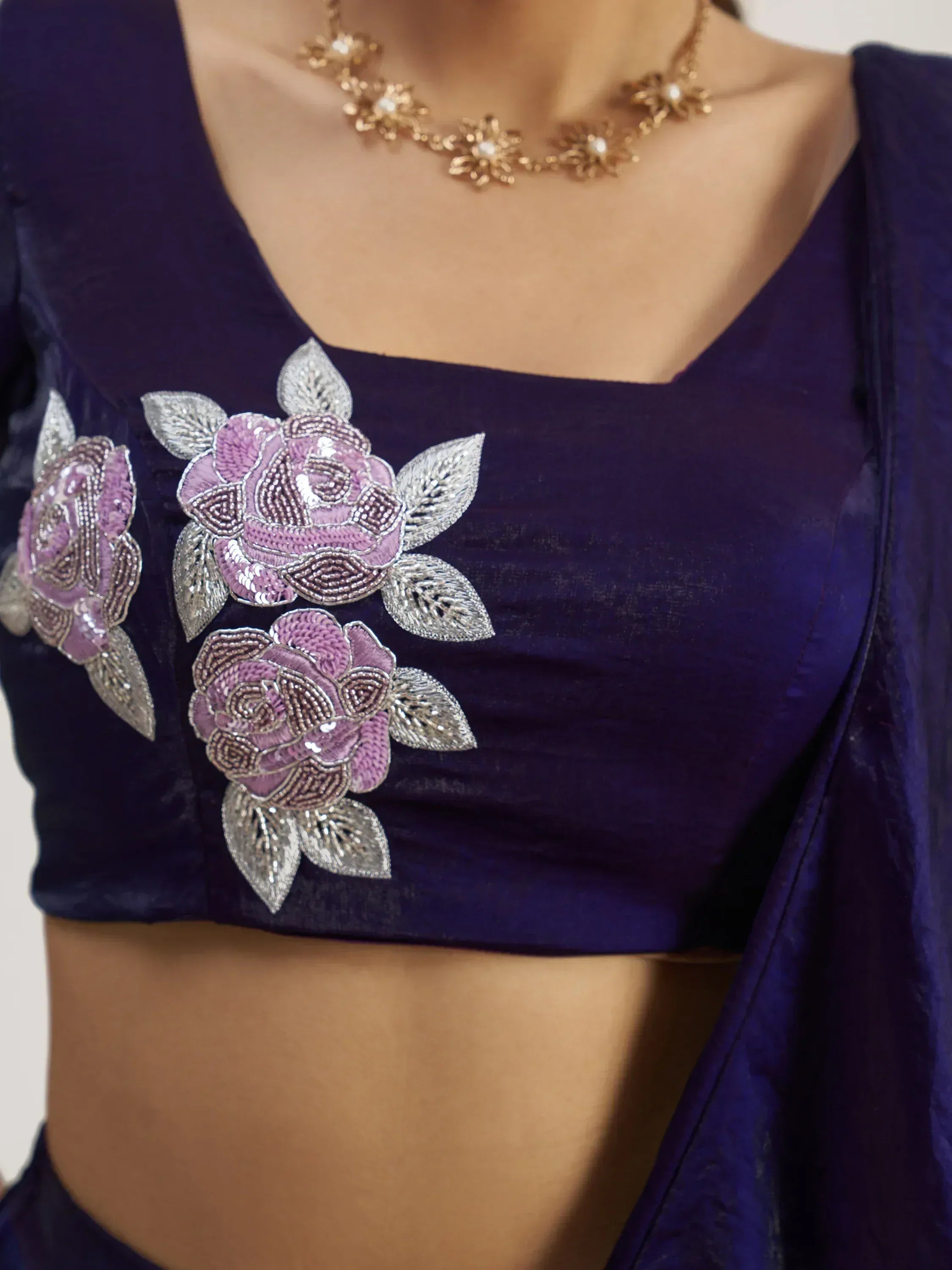 Purple velvet blouse with floral embroidery and silver leaves, paired with matching saree.