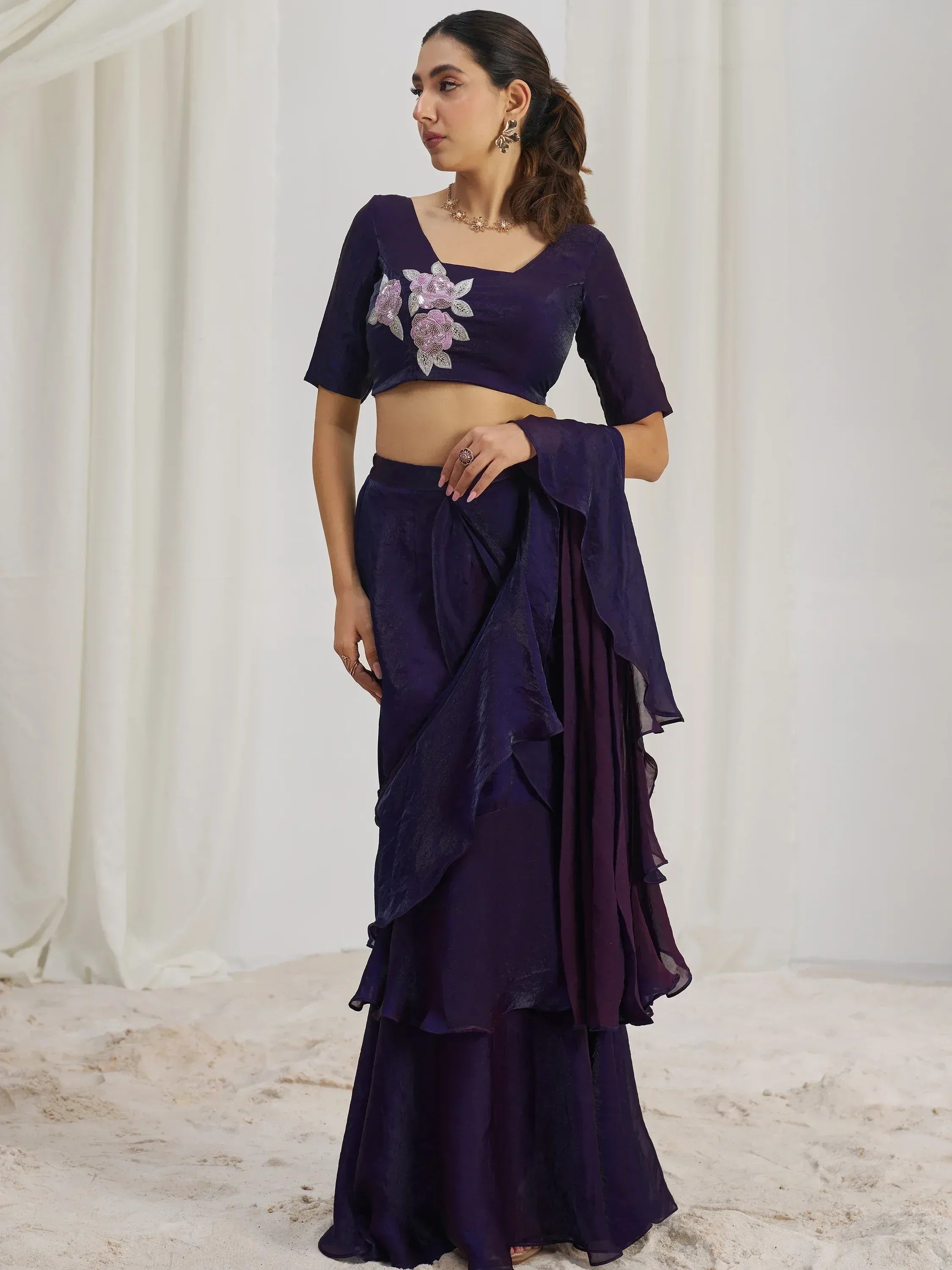 Elegant purple ethnic gown with floral embroidery and ruffled layers, perfect for Indian occasions.