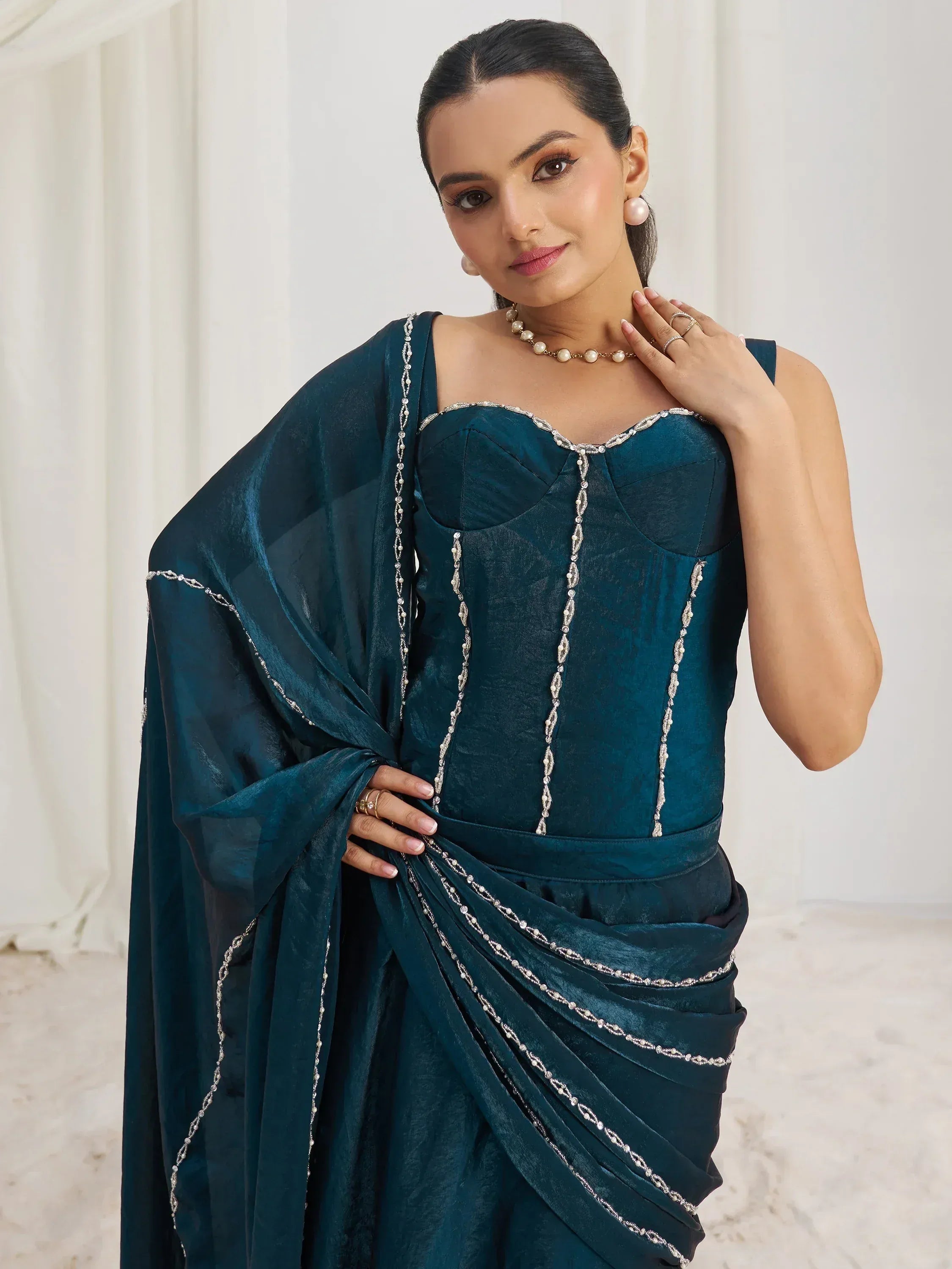 Elegant teal ethnic gown with pearl embellishments and draped design for festive occasions