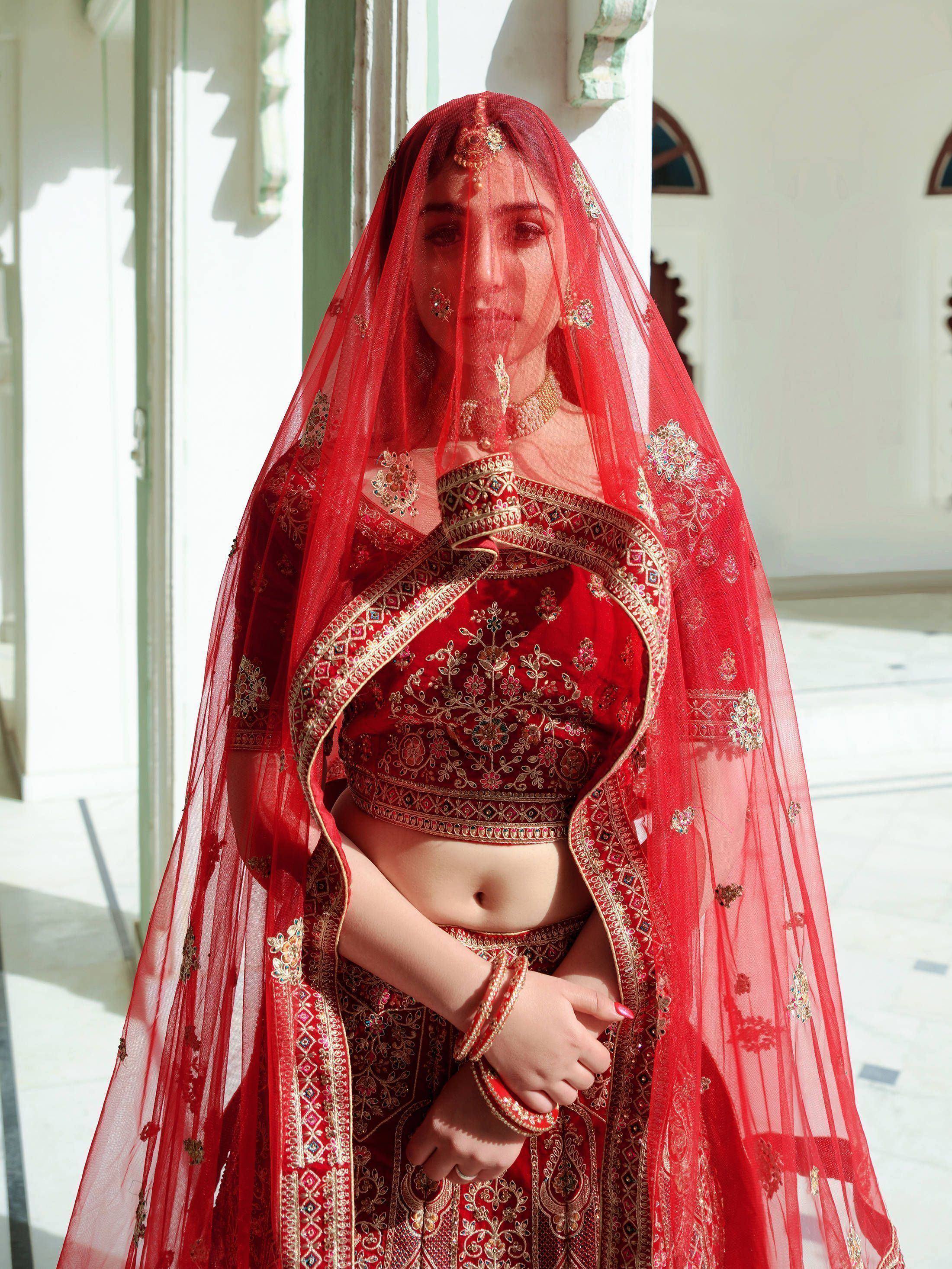 Red bridal lehenga choli with gold embroidery and sheer dupatta, traditional Indian wedding attire