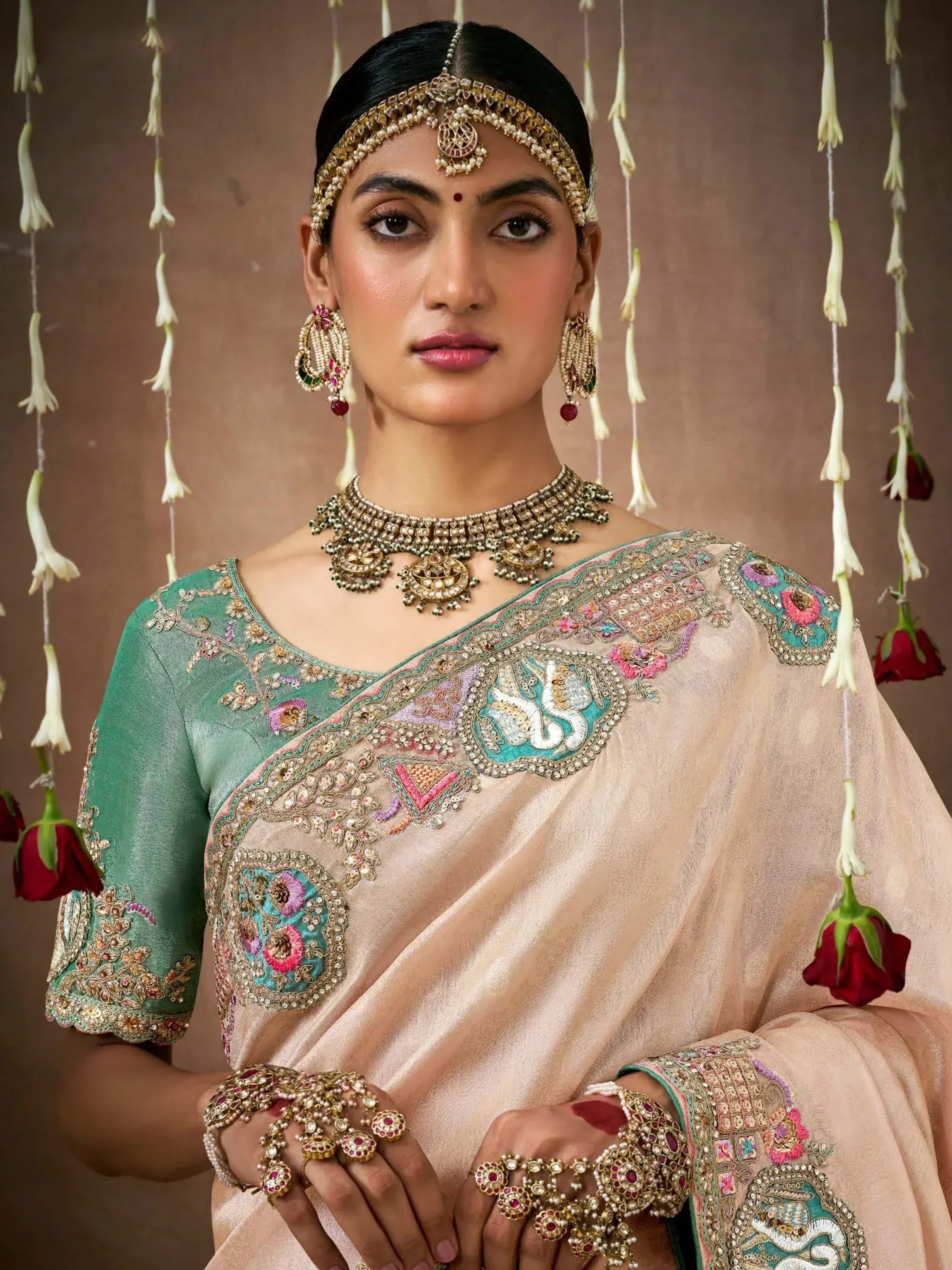 Elegant Indian saree with heavy embroidery, paired with traditional jewelry and floral backdrop