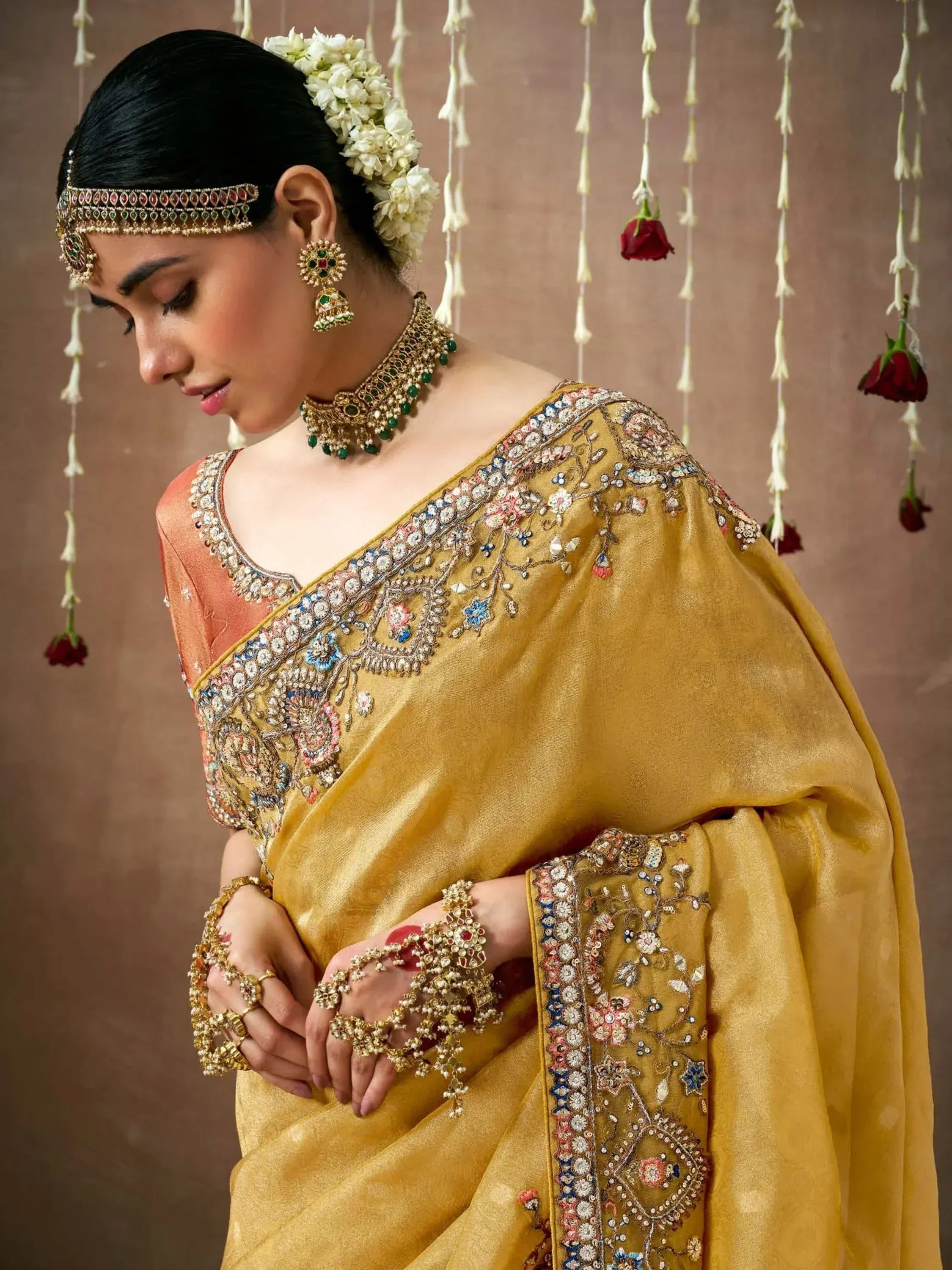 Elegant gold embroidered saree with floral motifs, traditional jewelry, and floral hair accessory for Indian ethnic wear