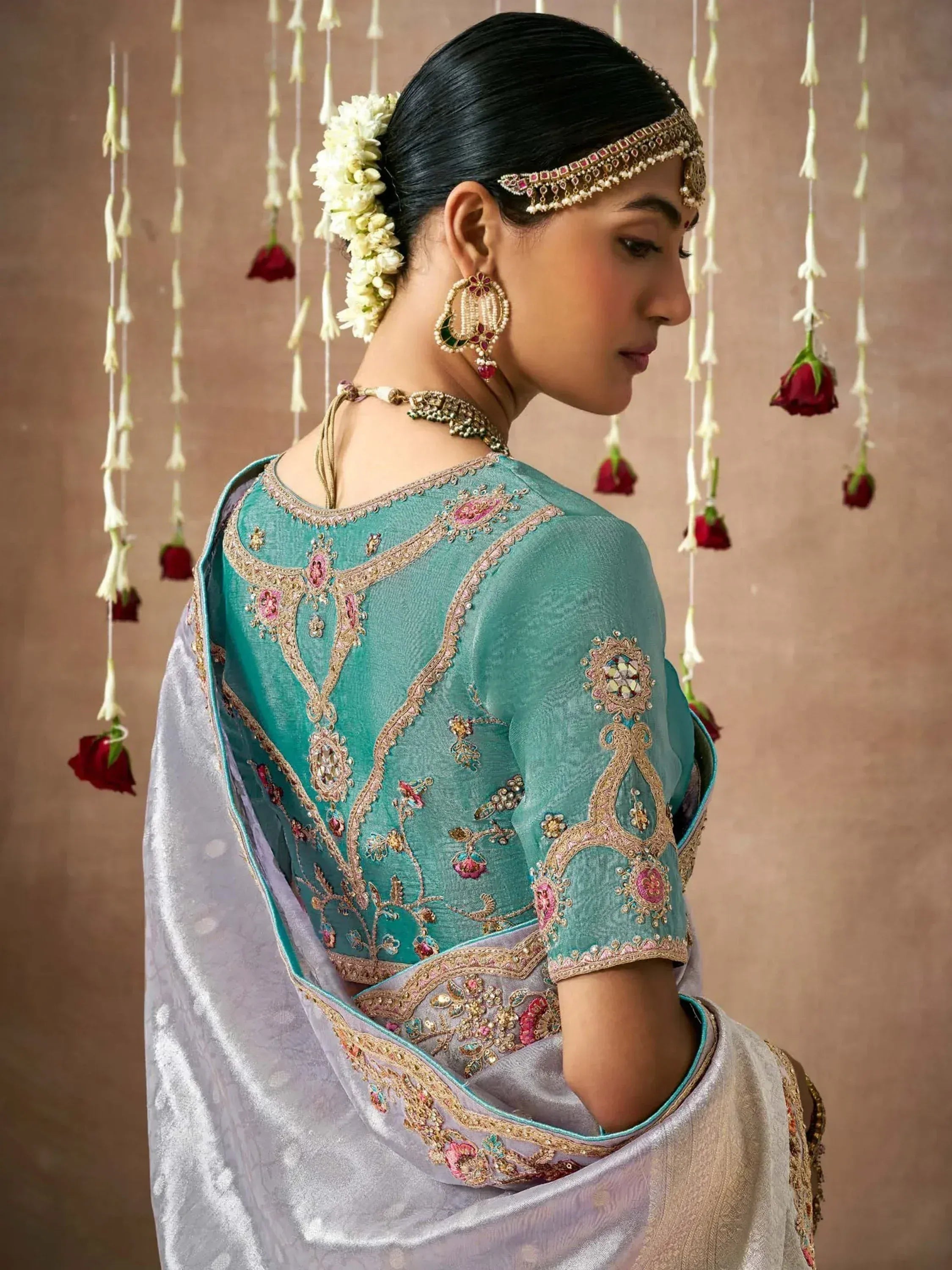 Elegant teal designer lehenga choli with intricate gold embroidery, floral motifs, and traditional Indian bridal jewelry.