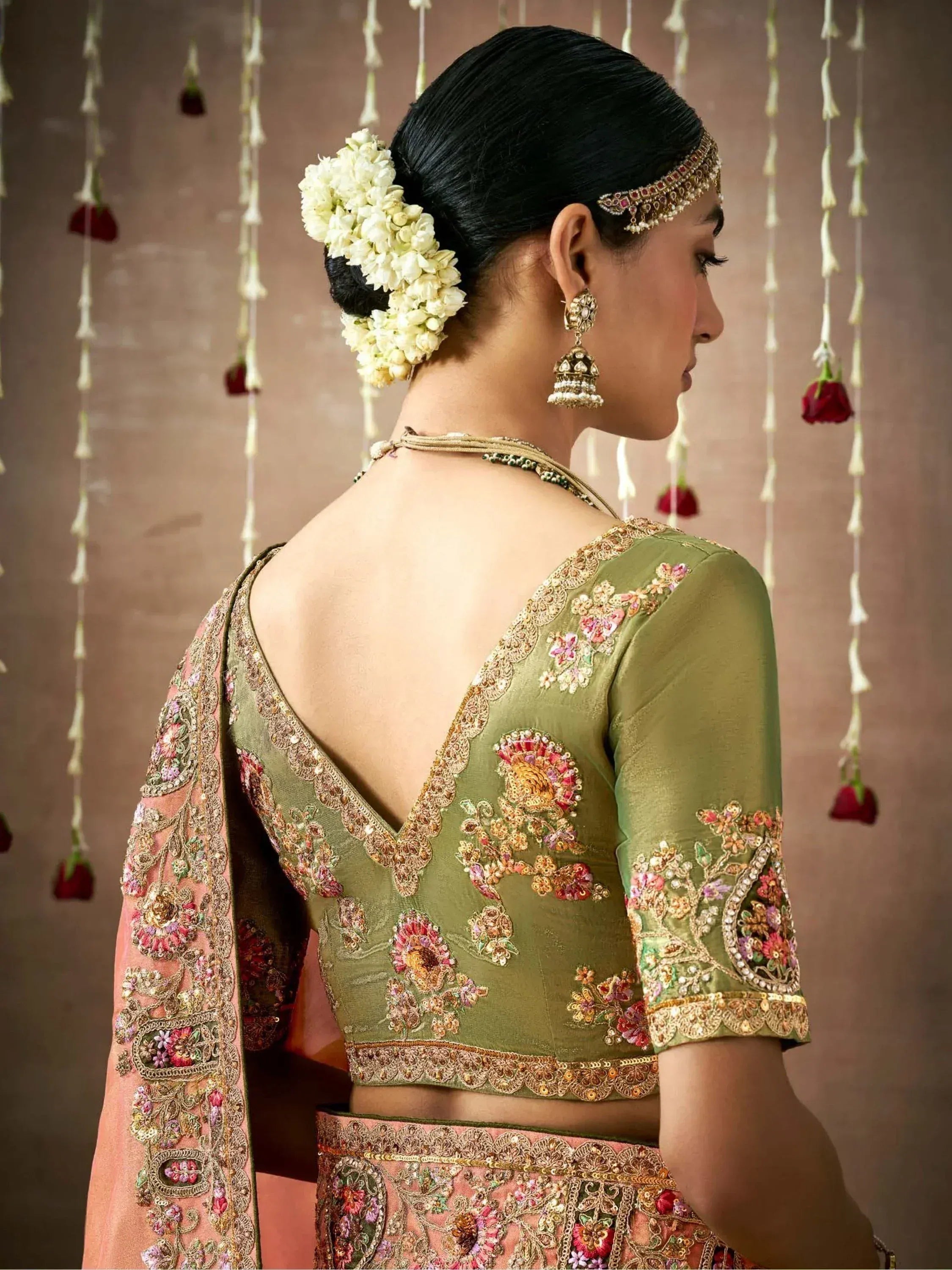 Olive green embroidered lehenga choli with floral motifs, backless blouse, and traditional Indian jewelry