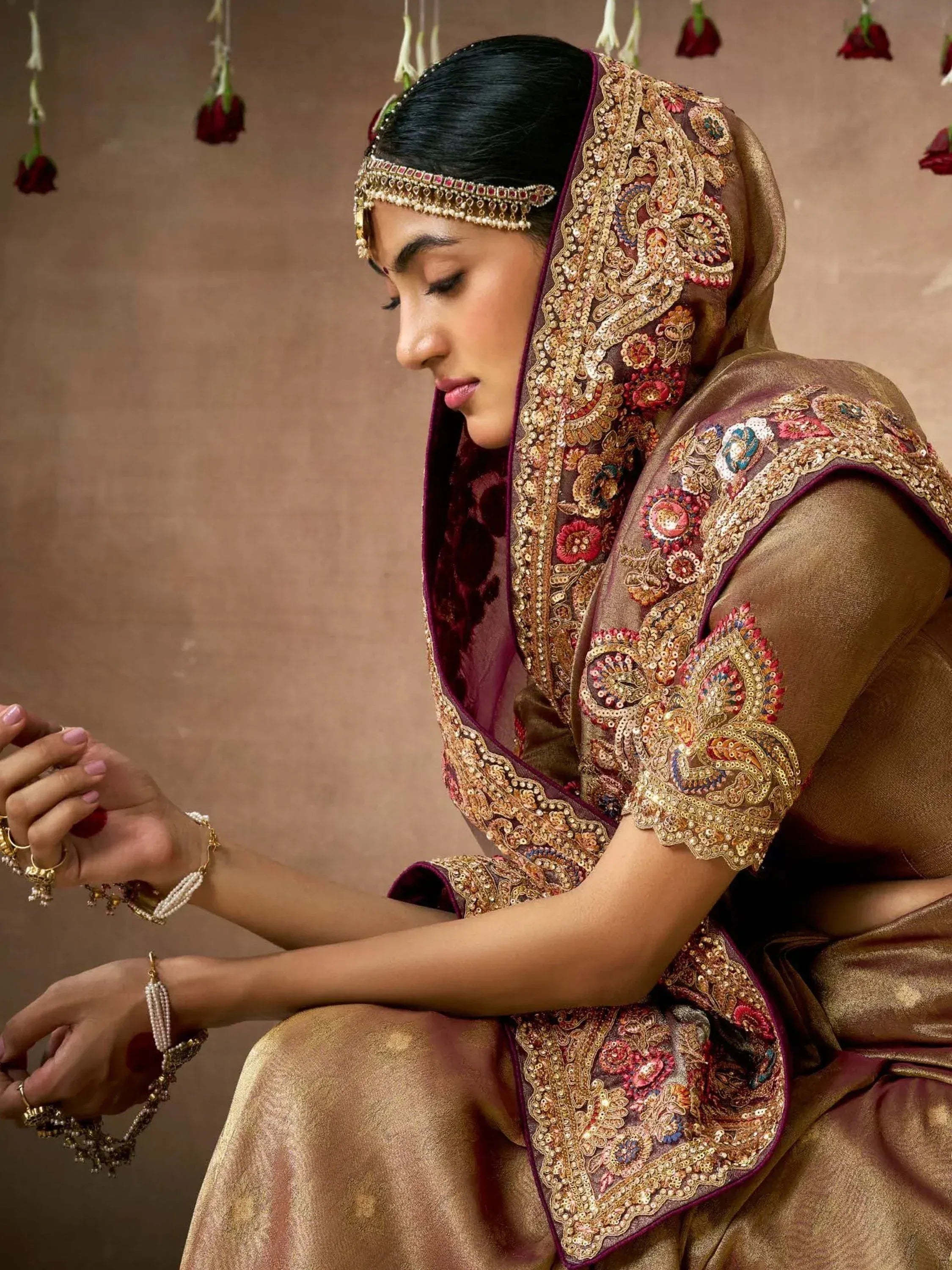 Elegant Indian bridal lehenga choli with intricate gold embroidery, maroon dupatta, and traditional jewelry